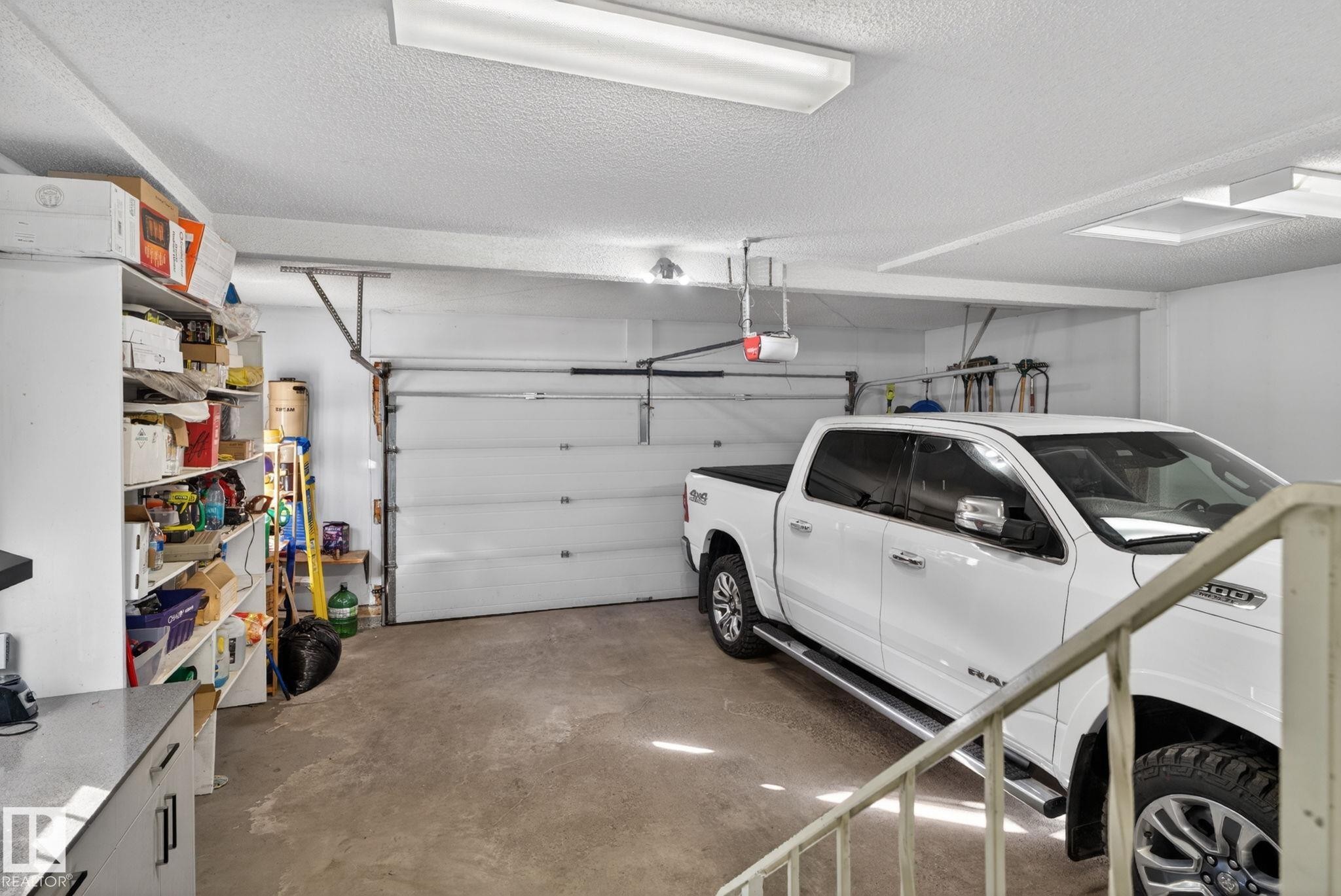 Attached garage with concrete flooring, automatic garage door opener, and overhead fluorescent lighting - 4615 43A Avenue, Edmonton, AB - Indoor Photo Showing Garage
