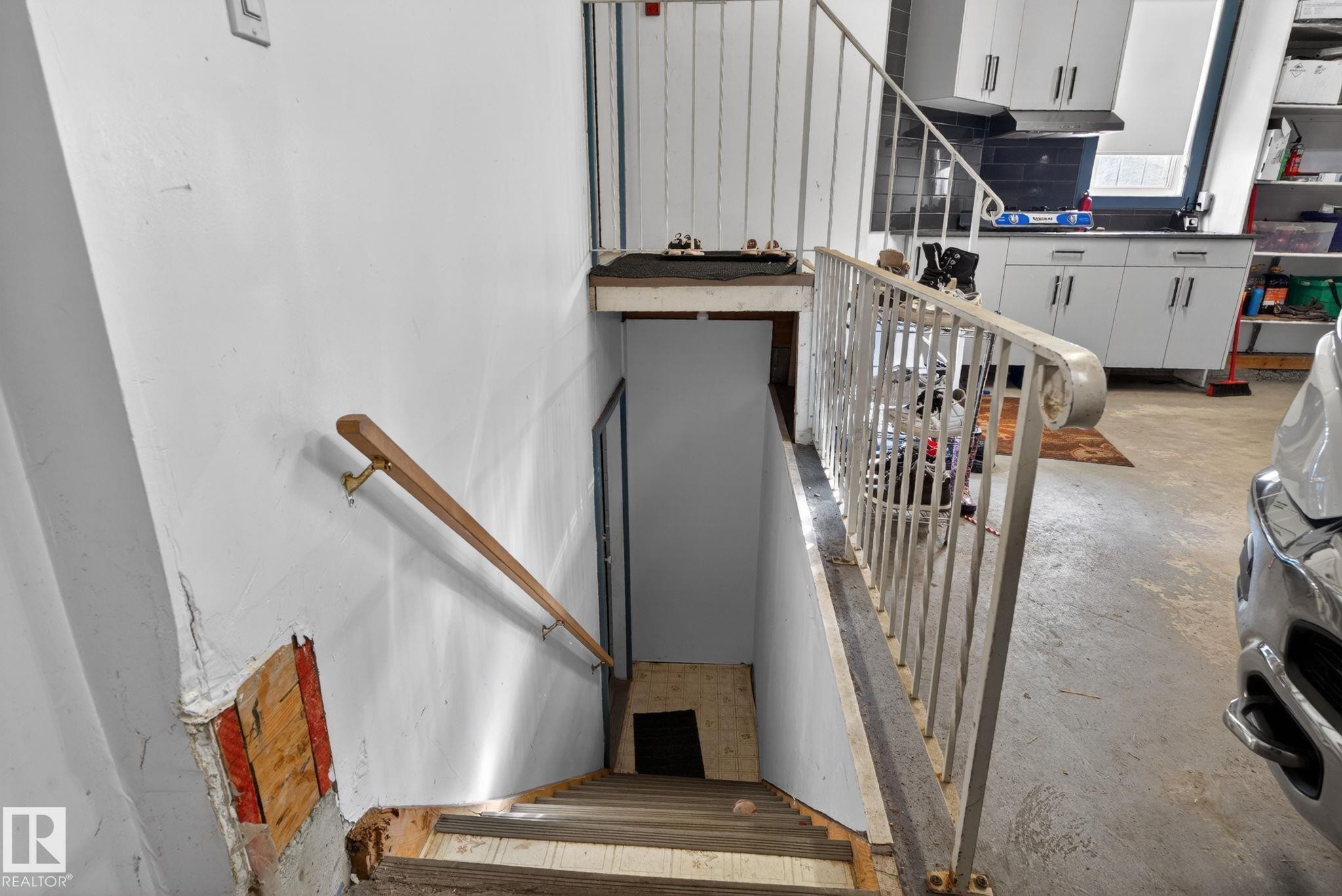Stairwell leading to lower level featuring a wooden handrail and metal railing - 4615 43A Avenue, Edmonton, AB - Indoor Photo Showing Other Room
