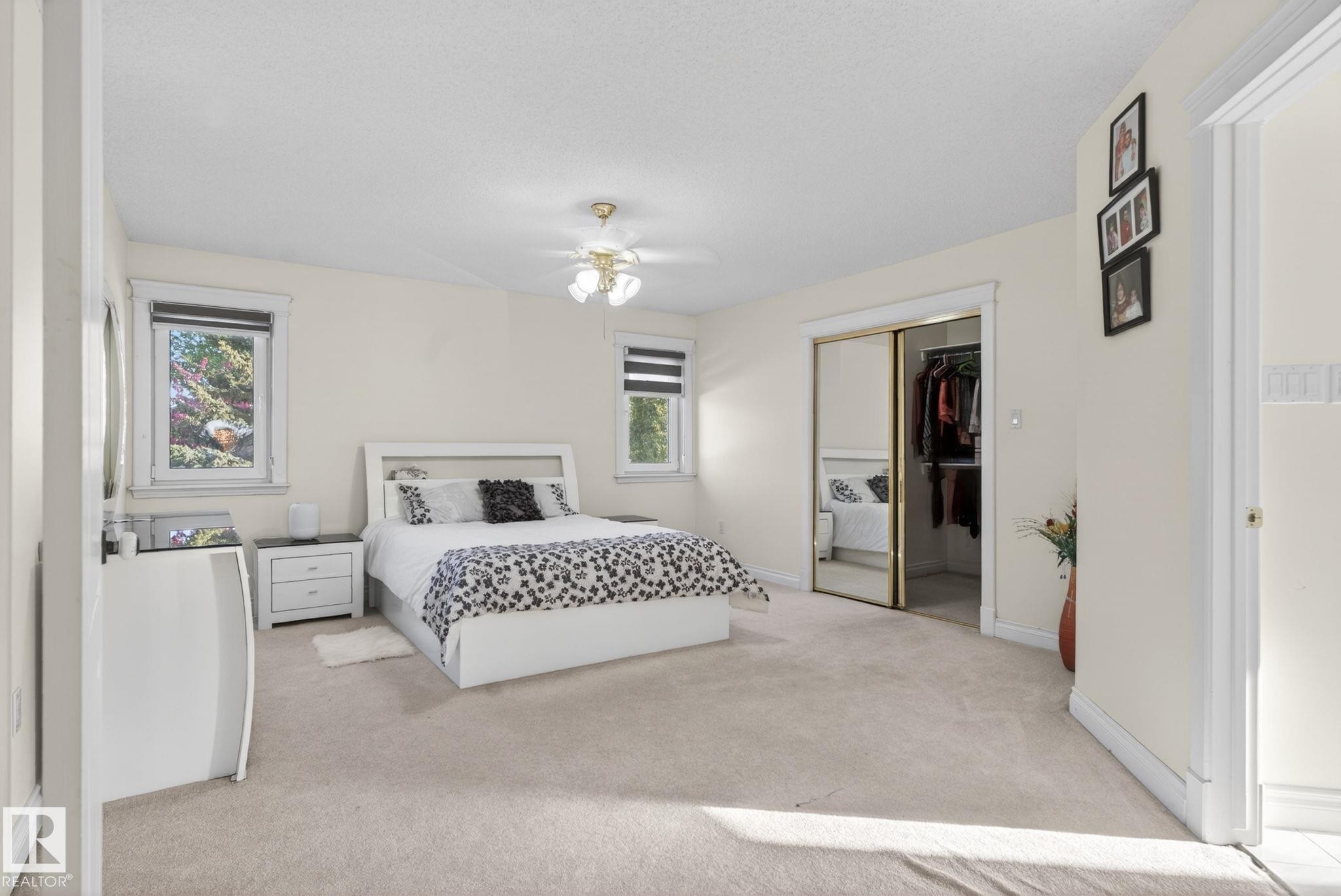 Carpeted bedroom with two windows and a ceiling fan light fixture - 4615 43A Avenue, Edmonton, AB - Indoor Photo Showing Bedroom