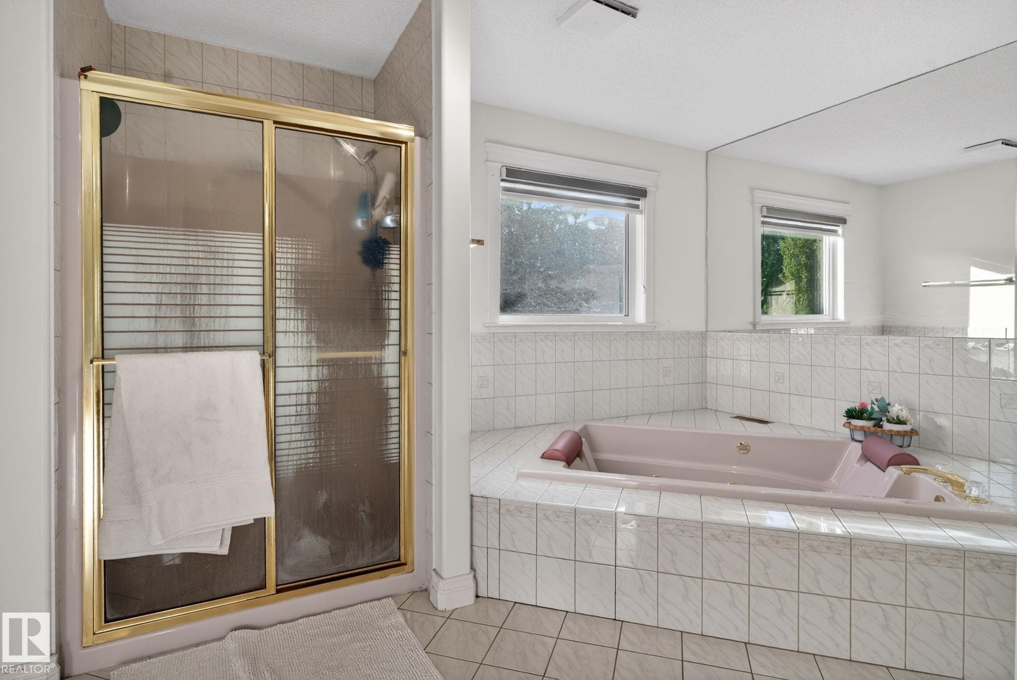 Soaking tub with tiled surround, two windows, and a full-wall mirror - 4615 43A Avenue, Edmonton, AB - Indoor Photo Showing Bathroom