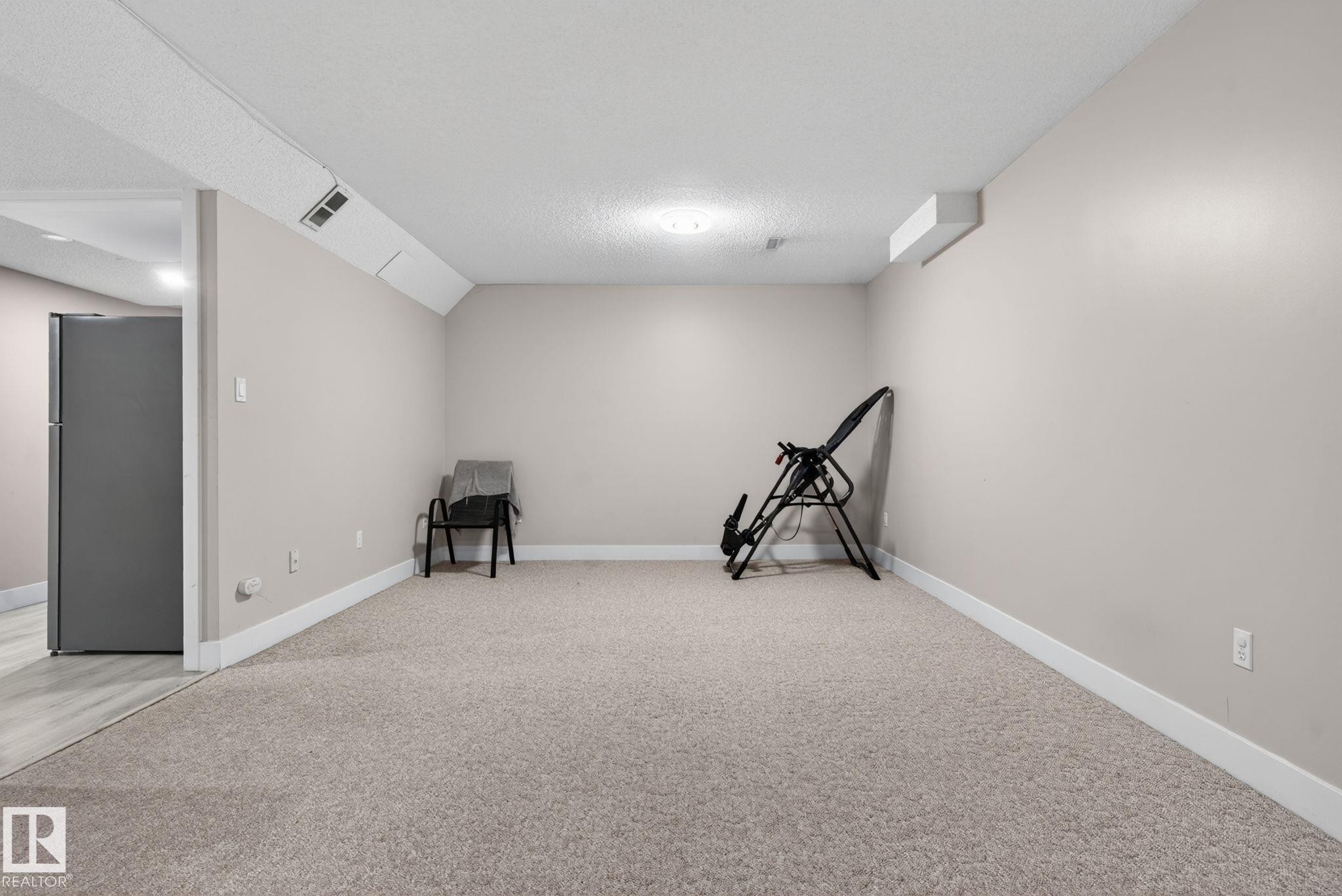 Spacious room featuring neutral wall paint, carpet flooring, recessed lighting, and white baseboards - 4615 43A Avenue, Edmonton, AB - Indoor