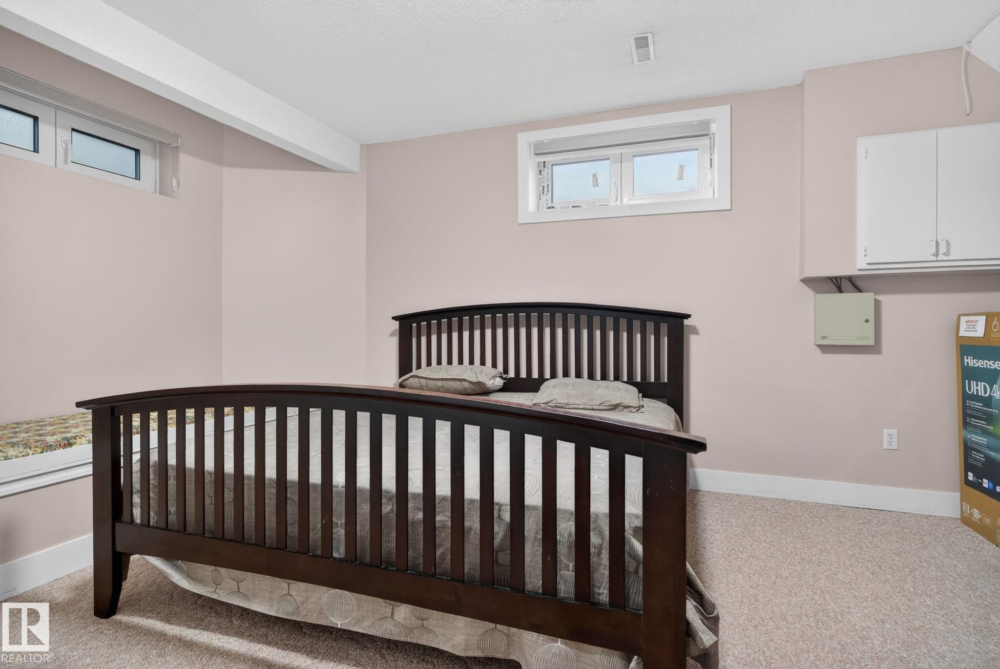 Carpeted room featuring two high-set windows with white trim, light-toned wall paint, and white baseboards - 4615 43A Avenue, Edmonton, AB - Indoor Photo Showing Bedroom