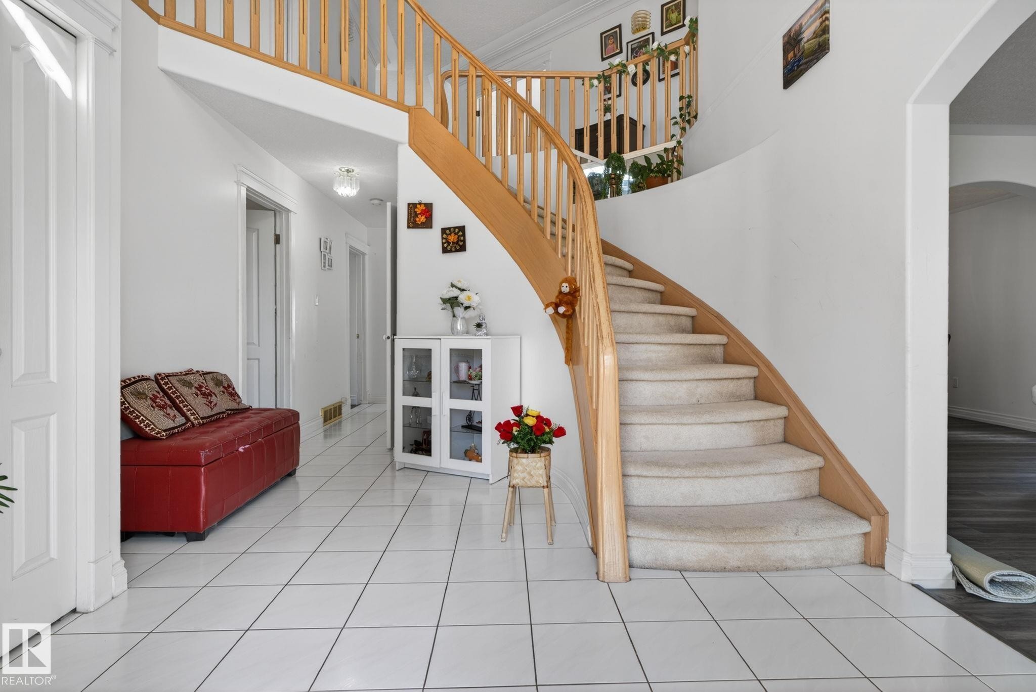 Grand curved staircase with light wood banister and carpeted treads - 4615 43A Avenue, Edmonton, AB - Indoor Photo Showing Other Room
