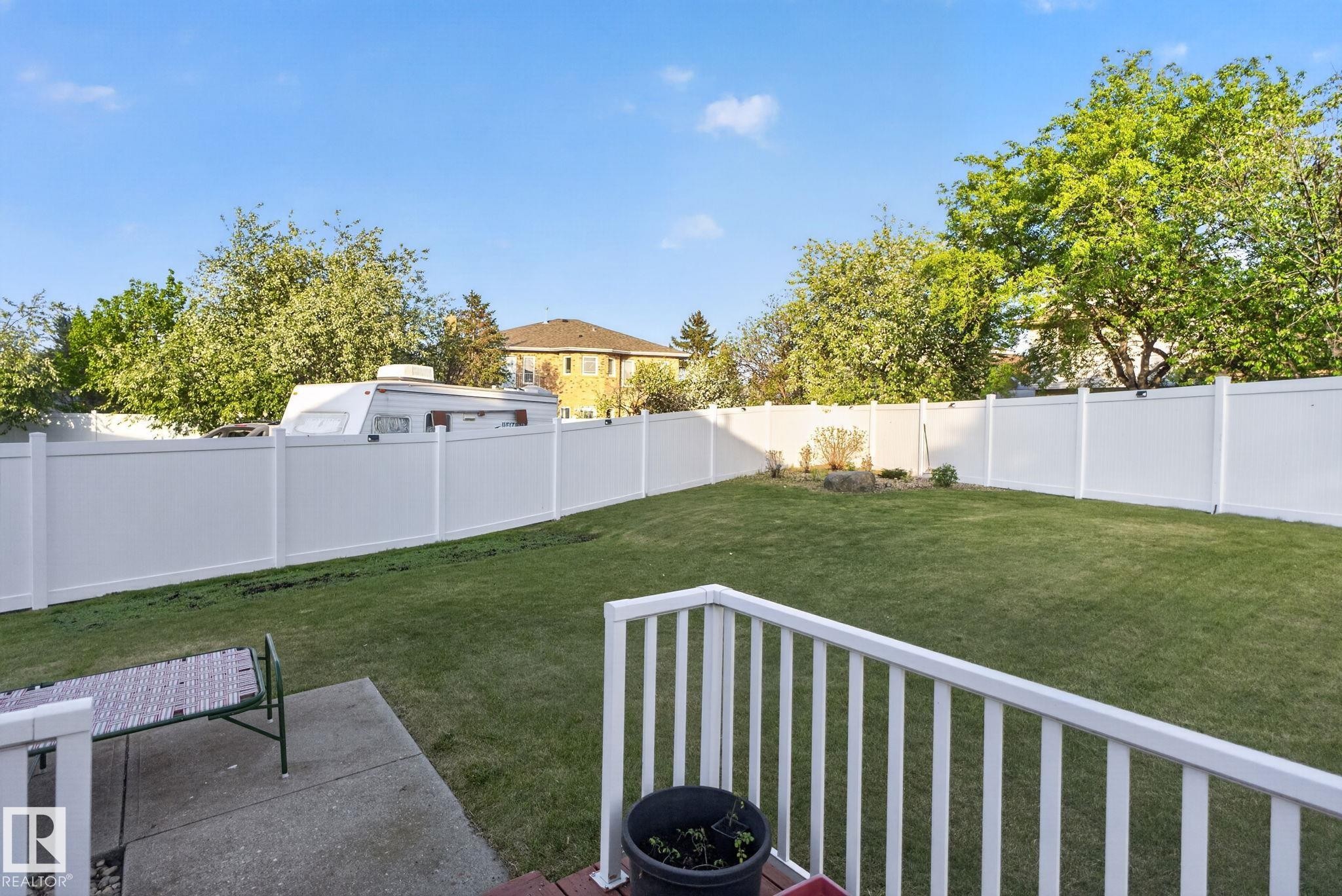 Expansive backyard featuring a large green lawn, a white privacy fence, and an established garden bed - 4615 43A Avenue, Edmonton, AB - Outdoor With Backyard