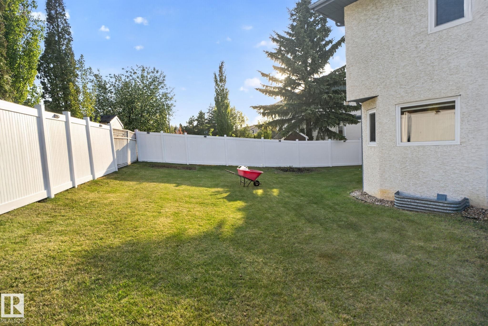 Expansive backyard featuring a green lawn, full perimeter white privacy fencing, and mature trees - 4615 43A Avenue, Edmonton, AB - Outdoor