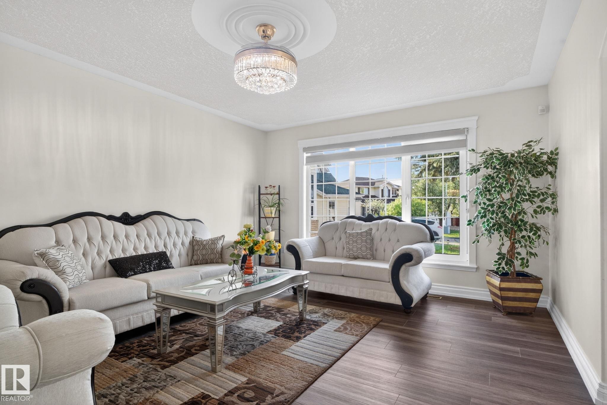 Spacious living area featuring dark wood-finish flooring, a large picture window, and crown molding - 4615 43A Avenue, Edmonton, AB - Indoor Photo Showing Living Room