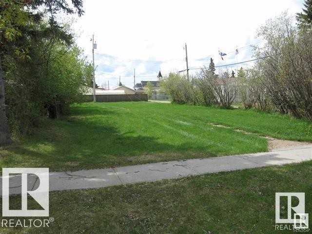 Generous parcel featuring a manicured lawn, established perimeter shrubbery, and a concrete sidewalk - 4927 50 Ave, Chipman, AB