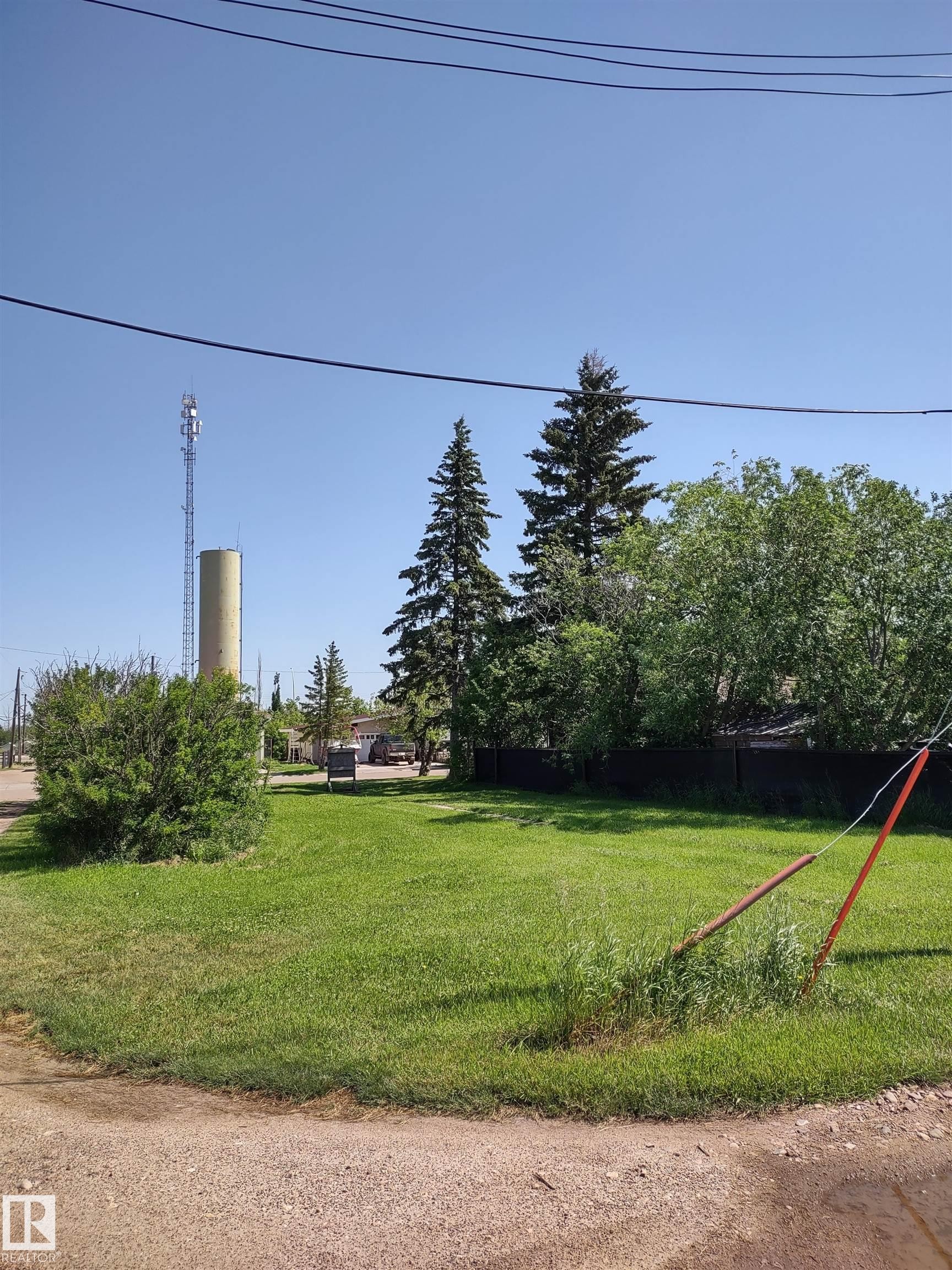 Spacious green lot featuring mature evergreen trees and established landscaping - 4927 50 Ave, Chipman, AB