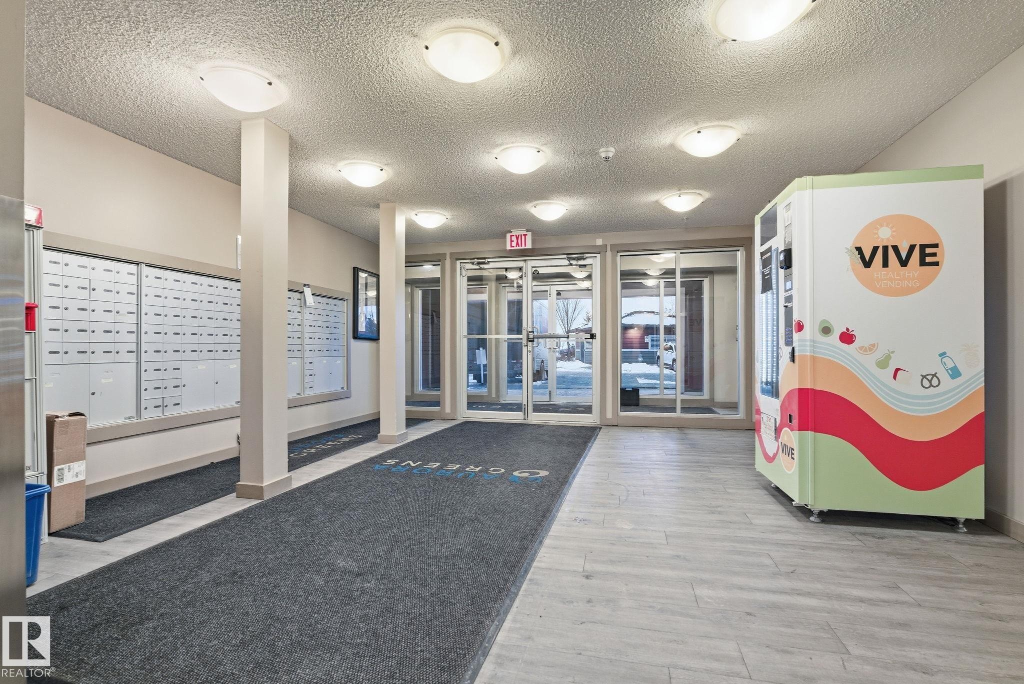Lobby area featuring light wood-finish flooring and a series of flush-mount ceiling lights - 424 1510 Watt Drive, Edmonton, AB
