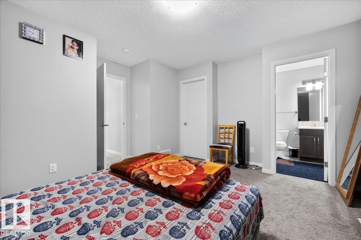 Spacious room with light gray walls, plush gray carpeting, and a private ensuite bathroom - 1187 Cy Becker Road, Edmonton, AB