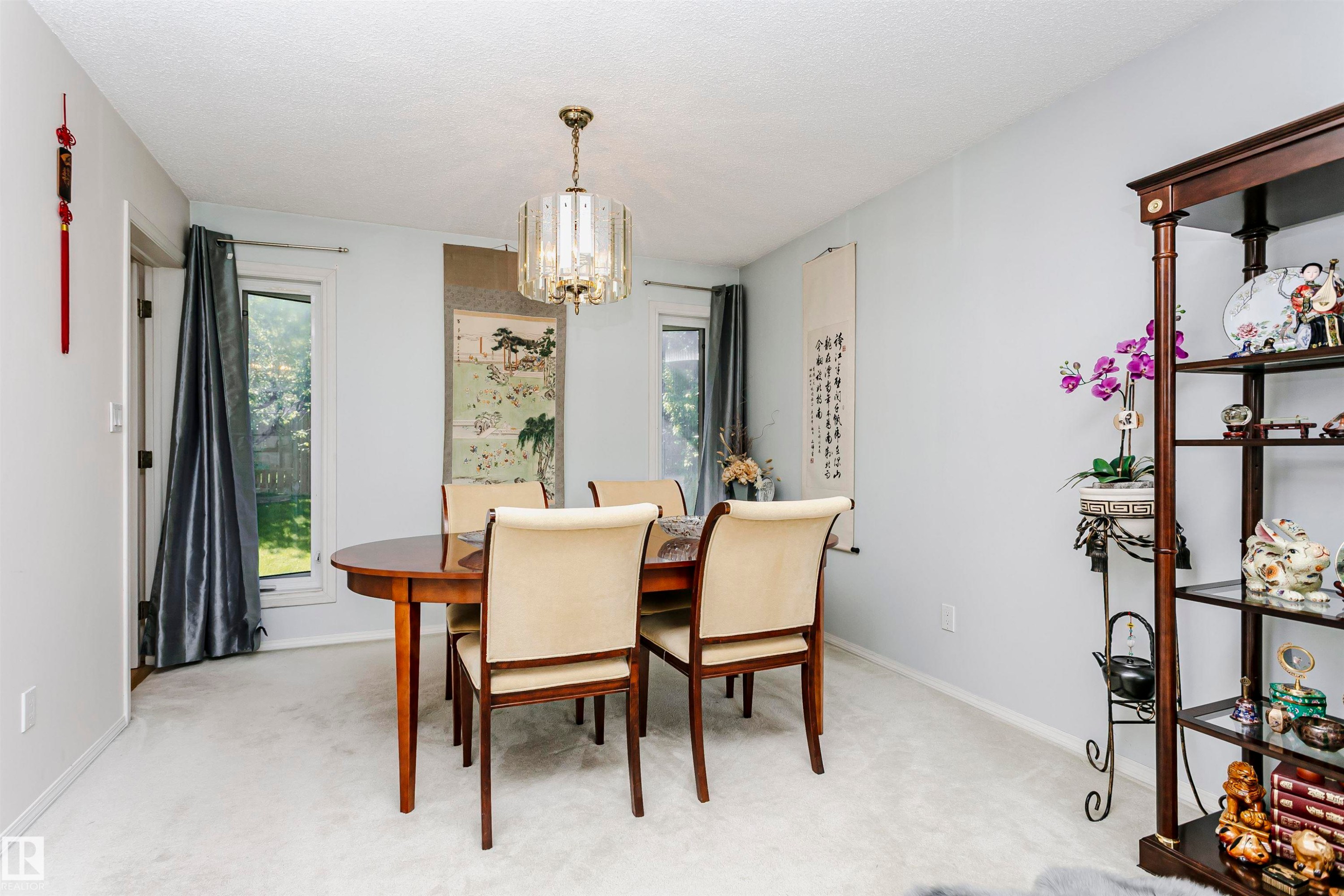 Dining area featuring light-colored carpeting, a central chandelier, and multiple windows - 11023 11A Avenue Nw, Edmonton, AB - Indoor Photo Showing Dining Room