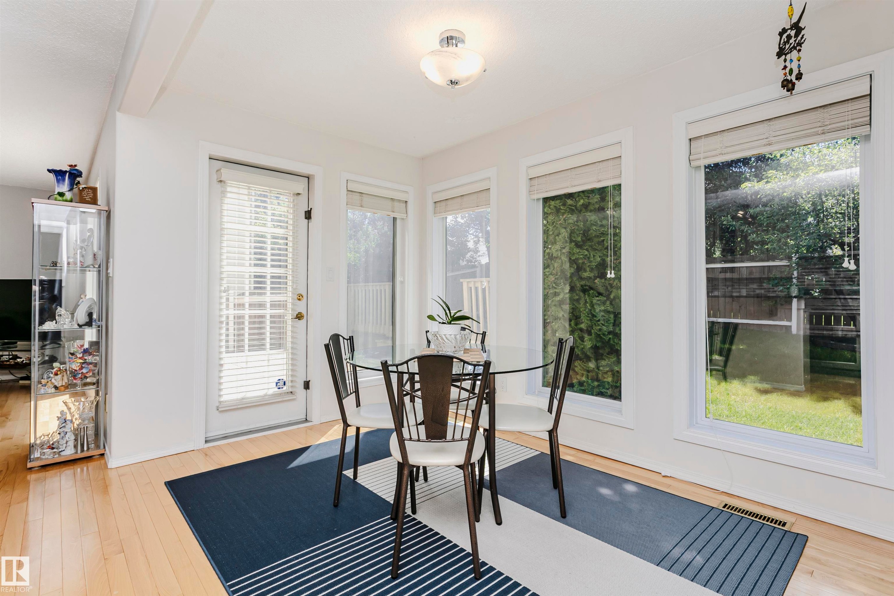 Dining area featuring wood-finish flooring, a white ceiling with a flush-mount light fixture, and multiple large windows providing ample natural light - 11023 11A Avenue Nw, Edmonton, AB - Indoor Photo Showing Other Room
