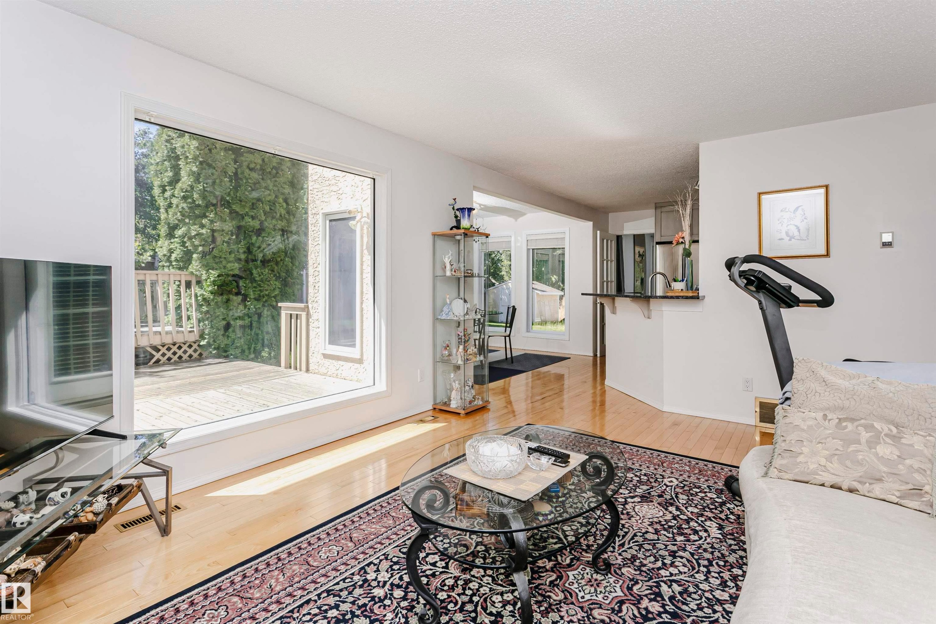 Spacious living area featuring hard surface flooring, a large picture window, and a built-in breakfast bar - 11023 11A Avenue Nw, Edmonton, AB - Indoor Photo Showing Other Room