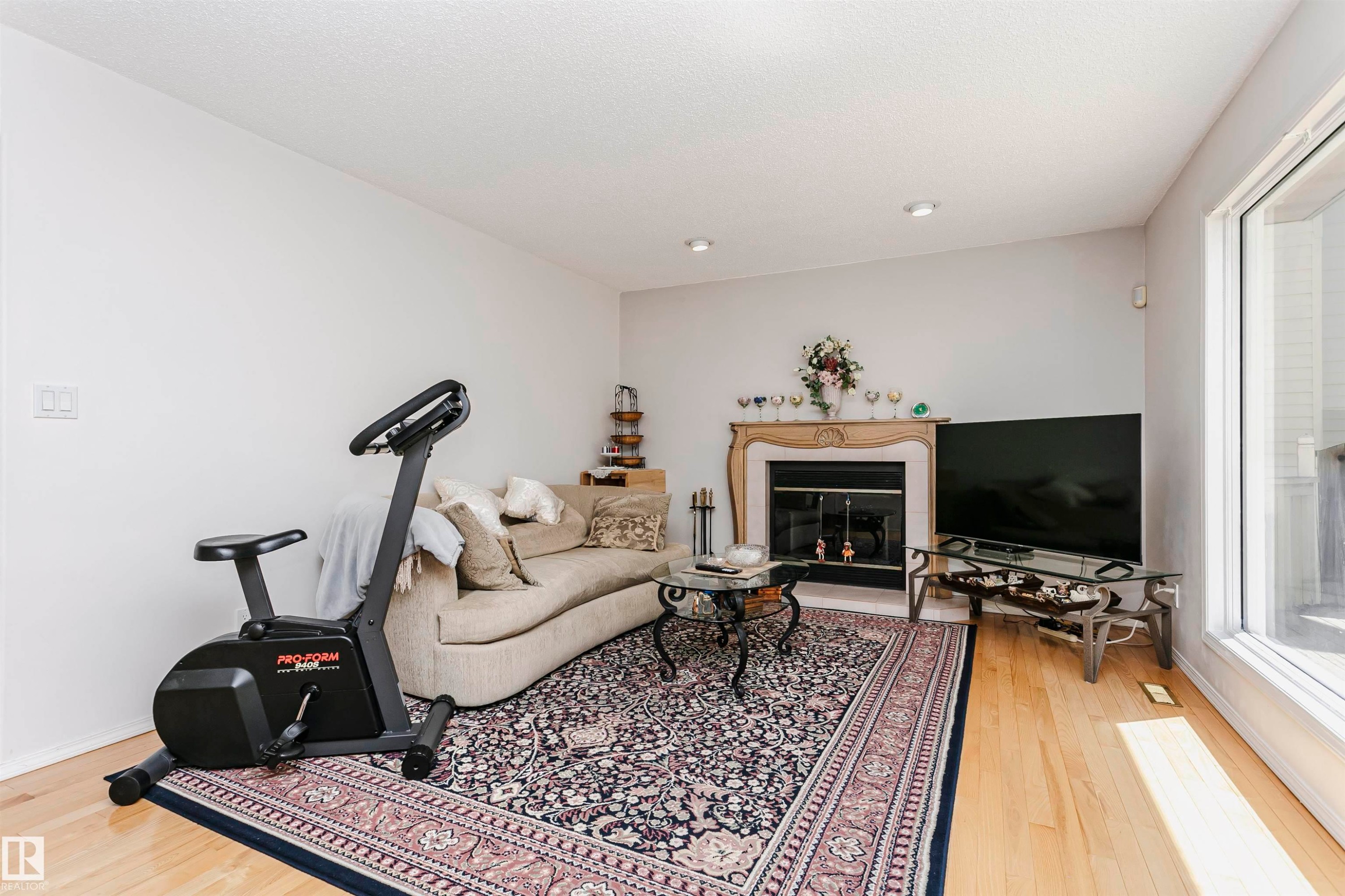 Living area featuring light wood-finish flooring, a decorative fireplace with a mantel, recessed lighting, and large windows - 11023 11A Avenue Nw, Edmonton, AB - Indoor With Fireplace