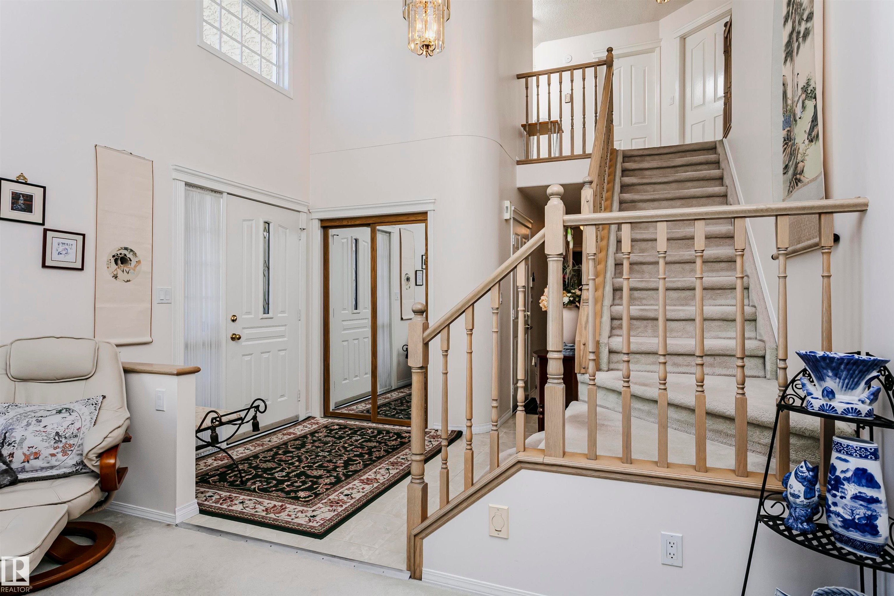 Two-story entry foyer featuring a grand staircase with wood railings and carpeted treads - 11023 11A Avenue Nw, Edmonton, AB - Indoor Photo Showing Other Room