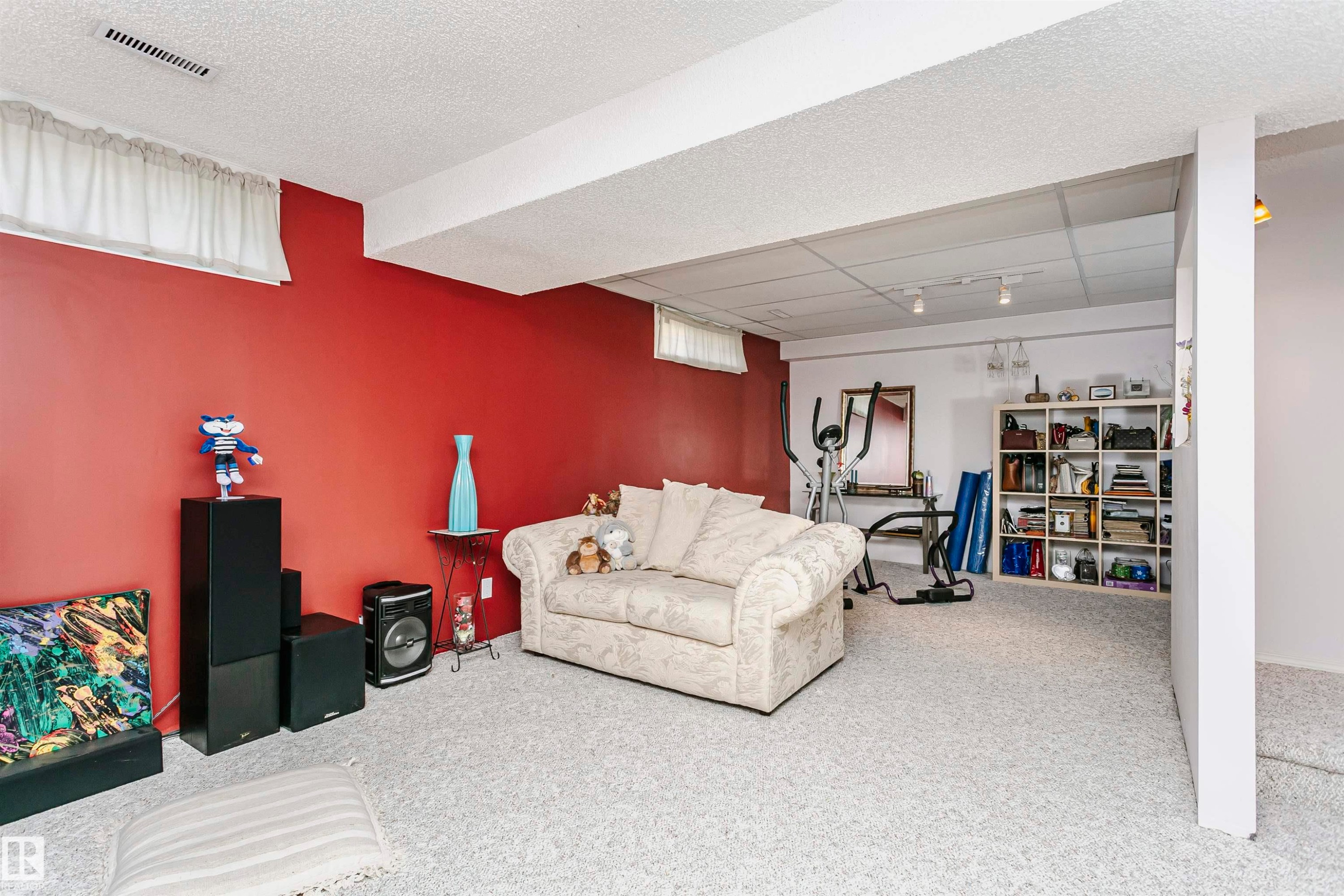 Spacious room featuring textured carpeting, a suspended ceiling with track lighting, and a vibrant accent wall - 11023 11A Avenue Nw, Edmonton, AB - Indoor