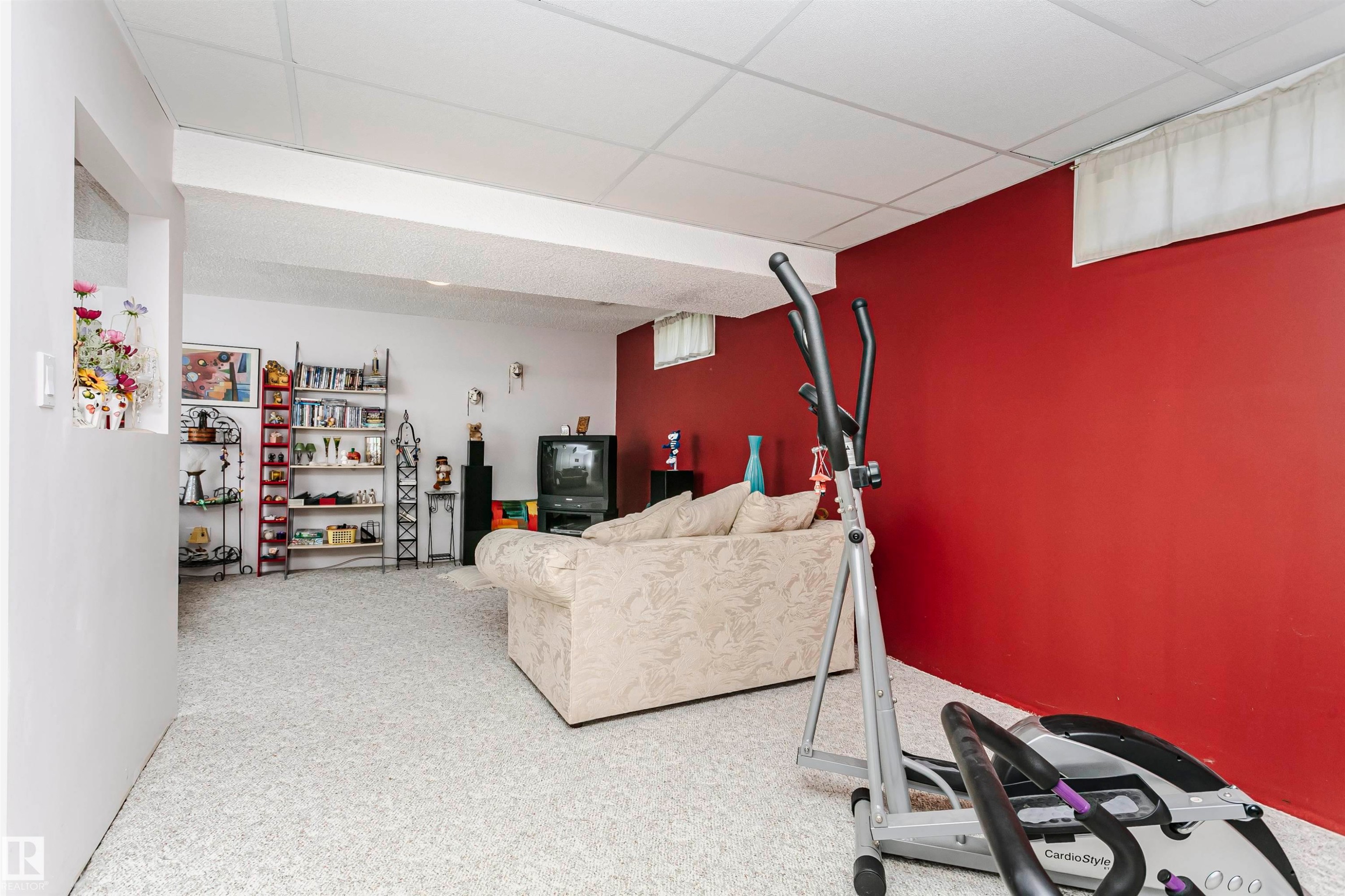 Carpeted lower level room featuring a drop-tile ceiling and a partial wall opening - 11023 11A Avenue Nw, Edmonton, AB - Indoor