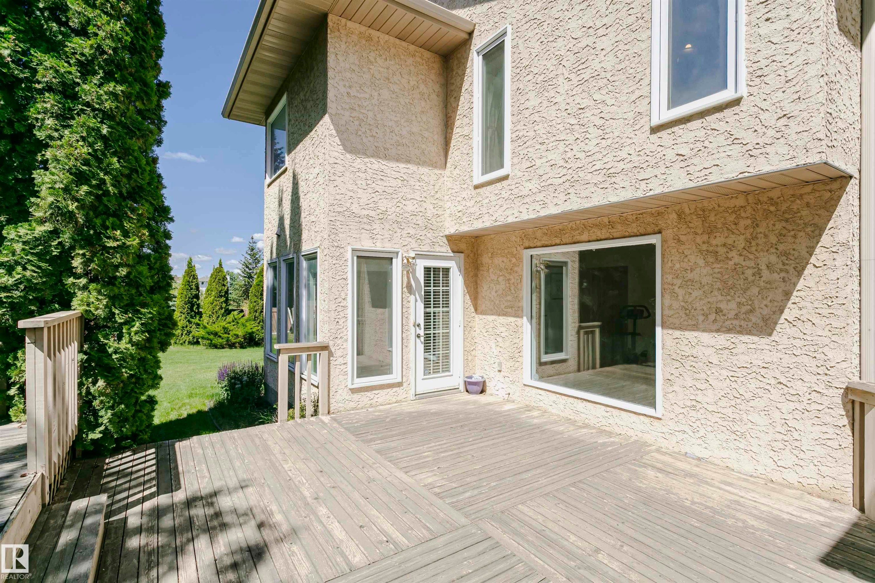 Spacious exterior wood deck with railing, providing access to the stucco-finished property - 11023 11A Avenue Nw, Edmonton, AB - Outdoor With Exterior