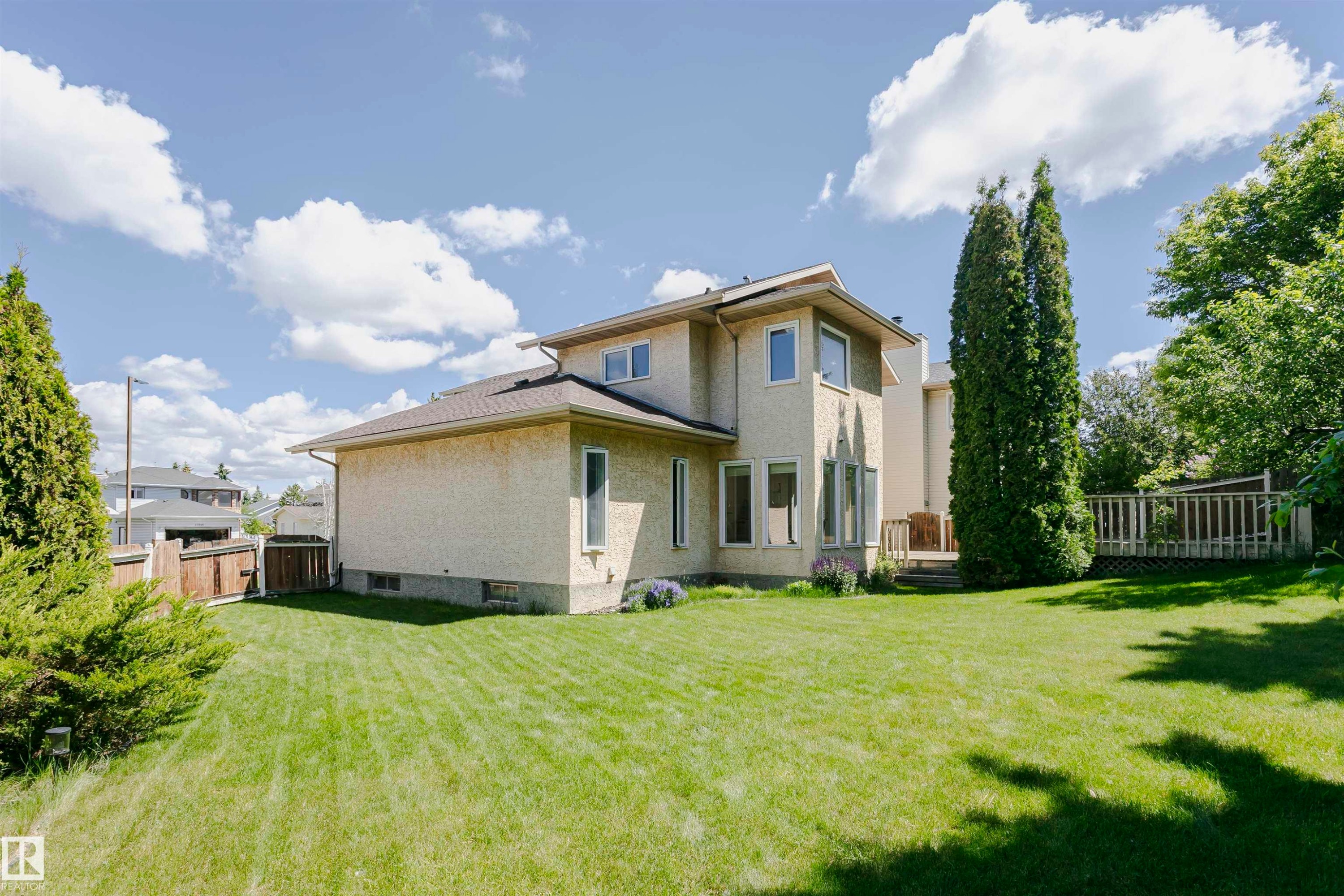 Spacious backyard with expansive lawn, stucco exterior, rear deck, and mature landscaping - 11023 11A Avenue Nw, Edmonton, AB - Outdoor