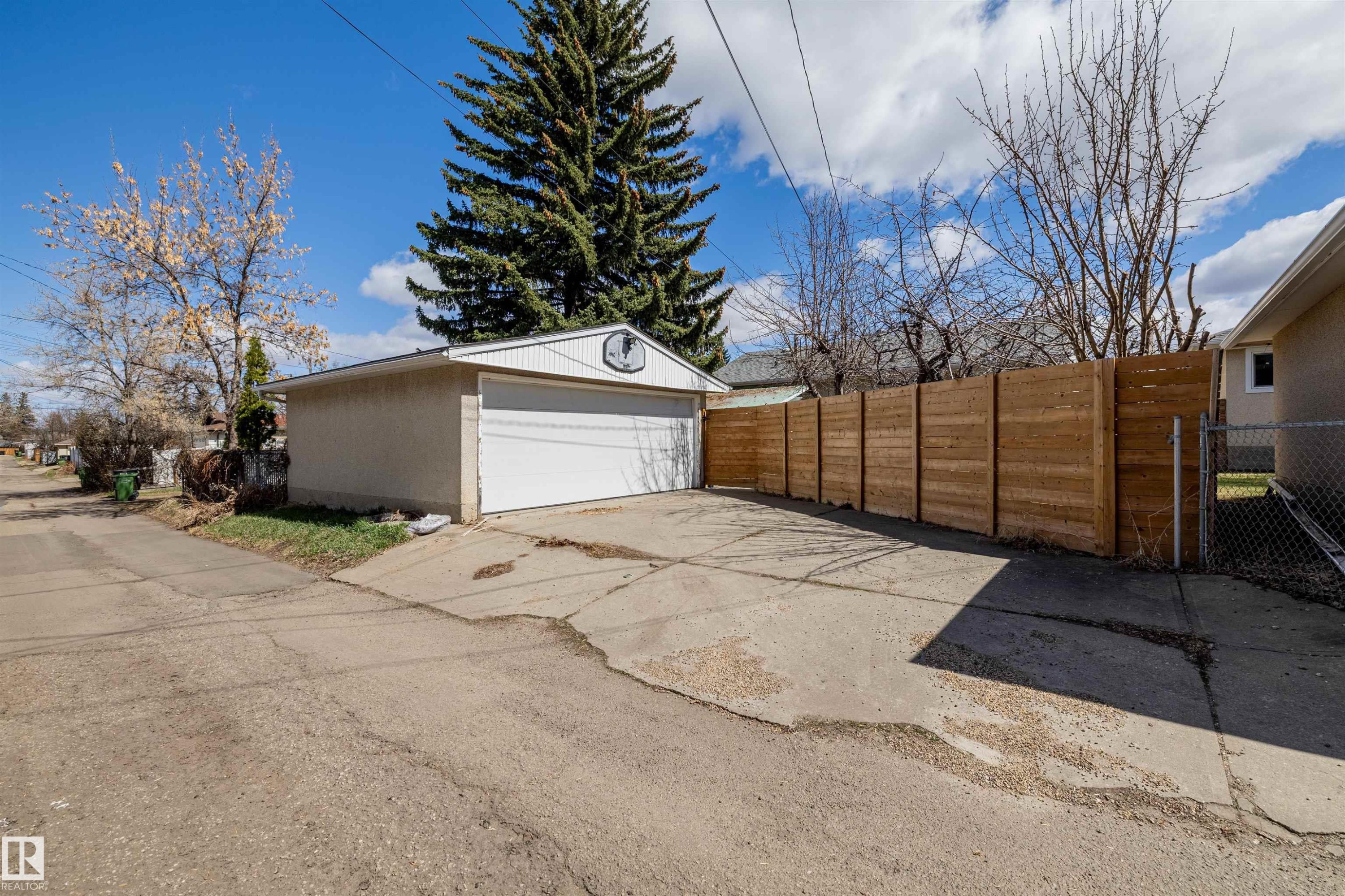 Detached two-car garage with a white overhead door and light-colored stucco exterior - 10130 62 Street, Edmonton, AB - Outdoor