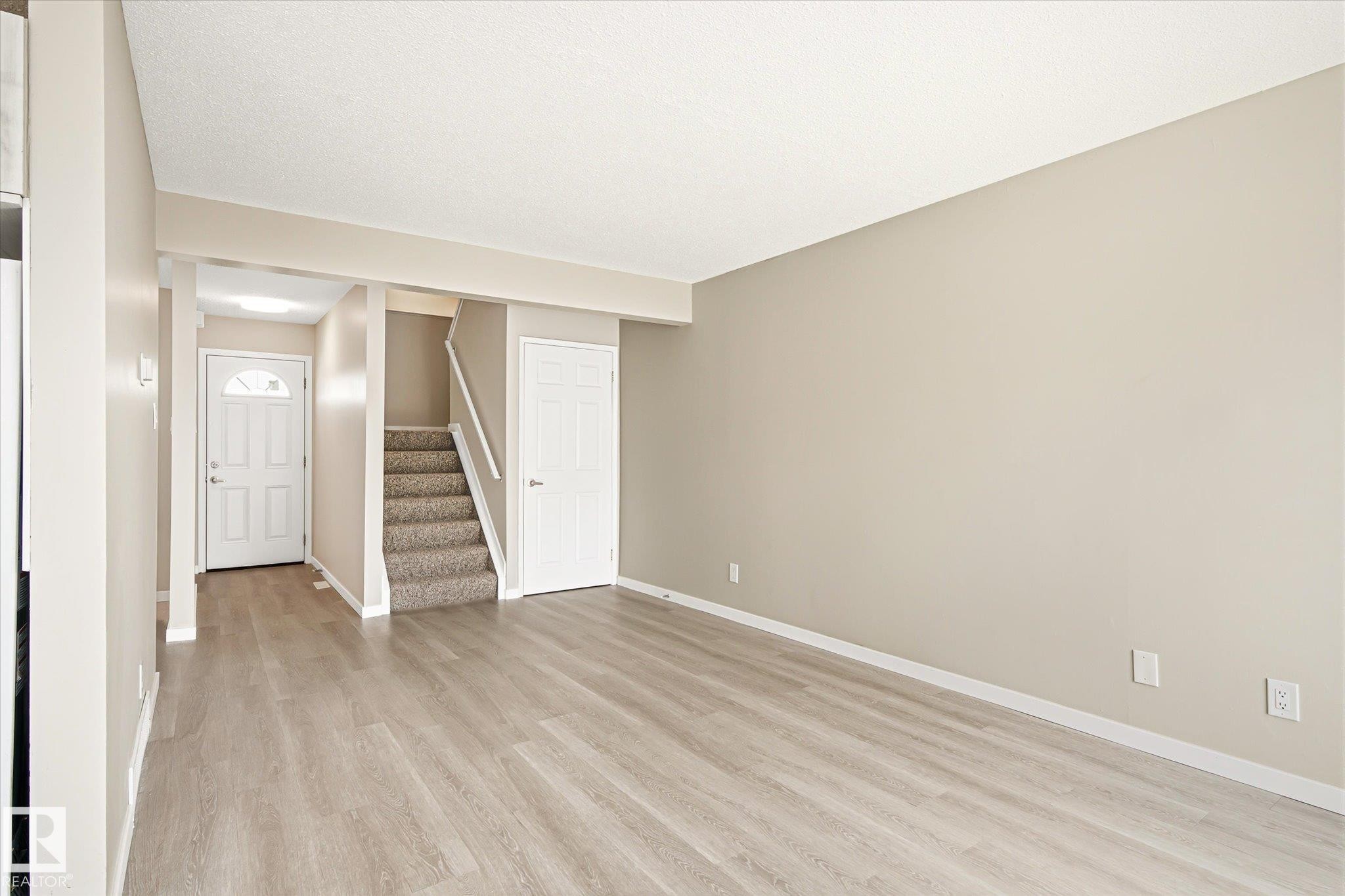 Open-concept living area featuring wood-finish flooring, neutral wall tones, and white trim - 186 Cornell Crest, Edmonton, AB