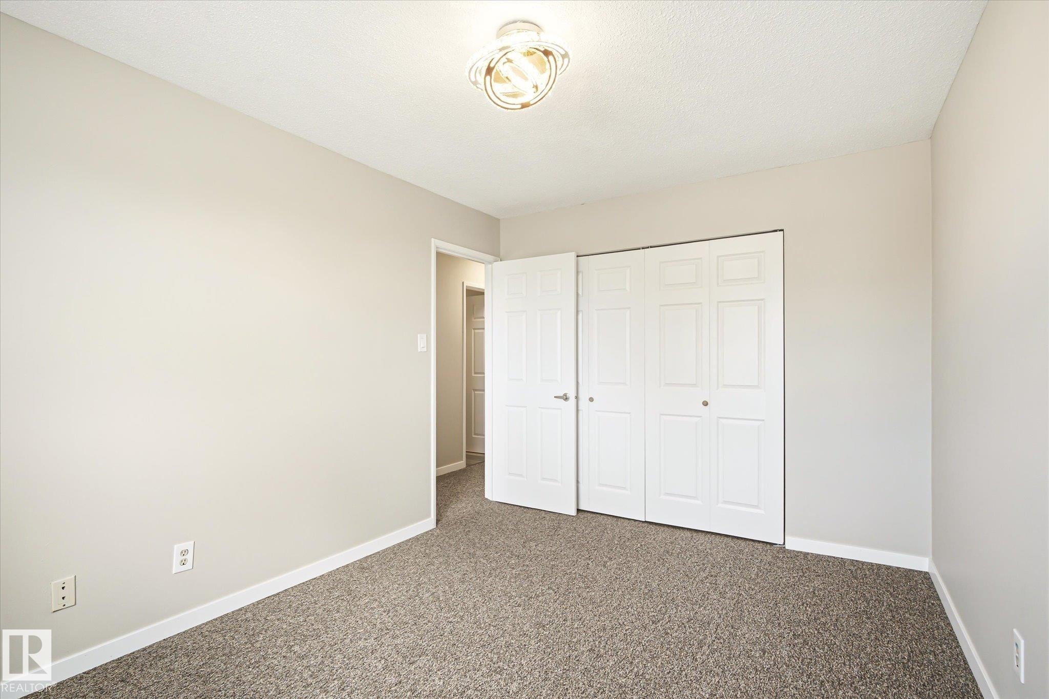 Neutral-toned room featuring light gray walls, textured carpeting, and white baseboards - 186 Cornell Crest, Edmonton, AB