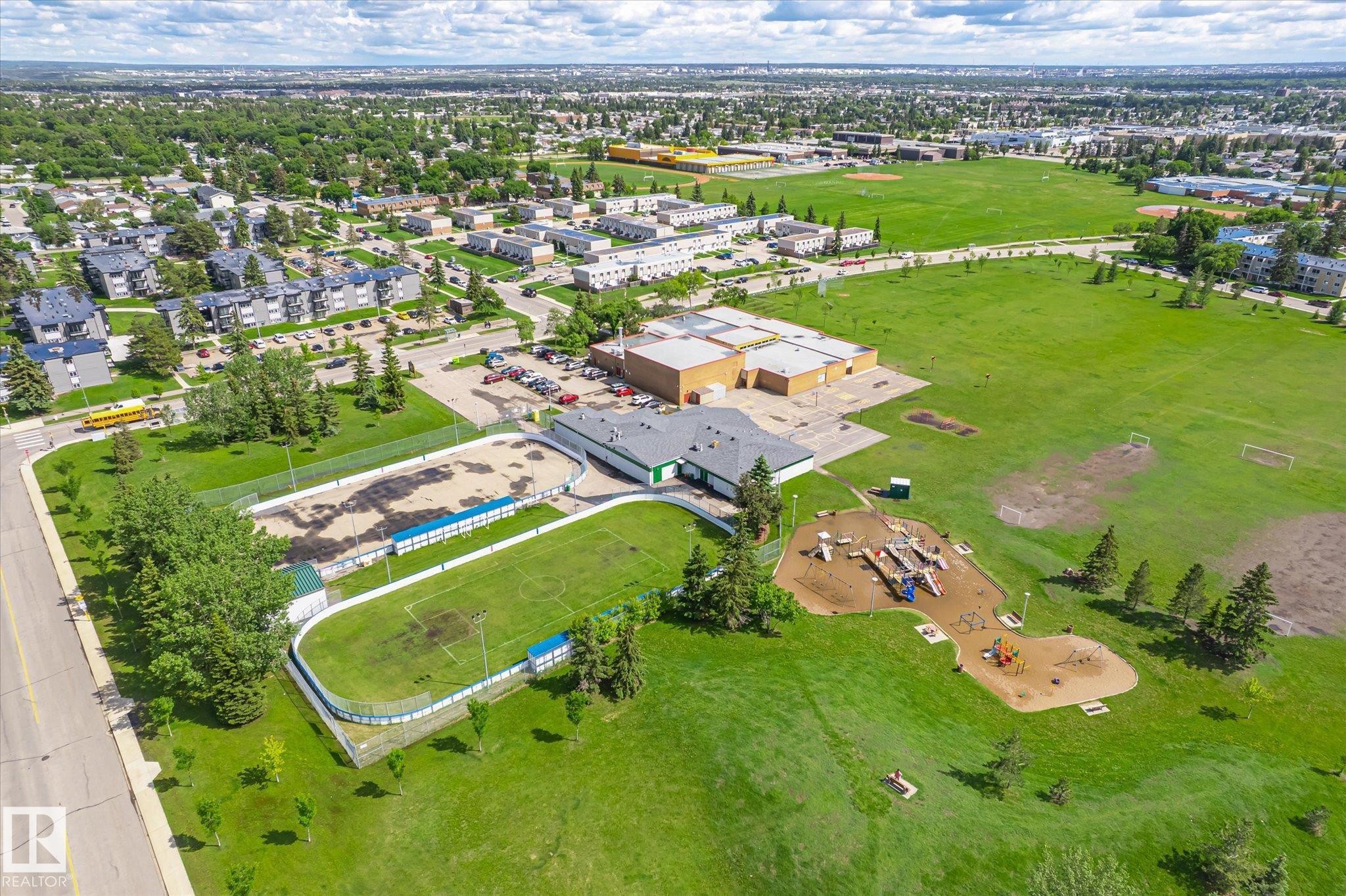 Expansive green space featuring multiple sports fields, an outdoor rink, and a playground area with various equipment - 186 Cornell Crest, Edmonton, AB