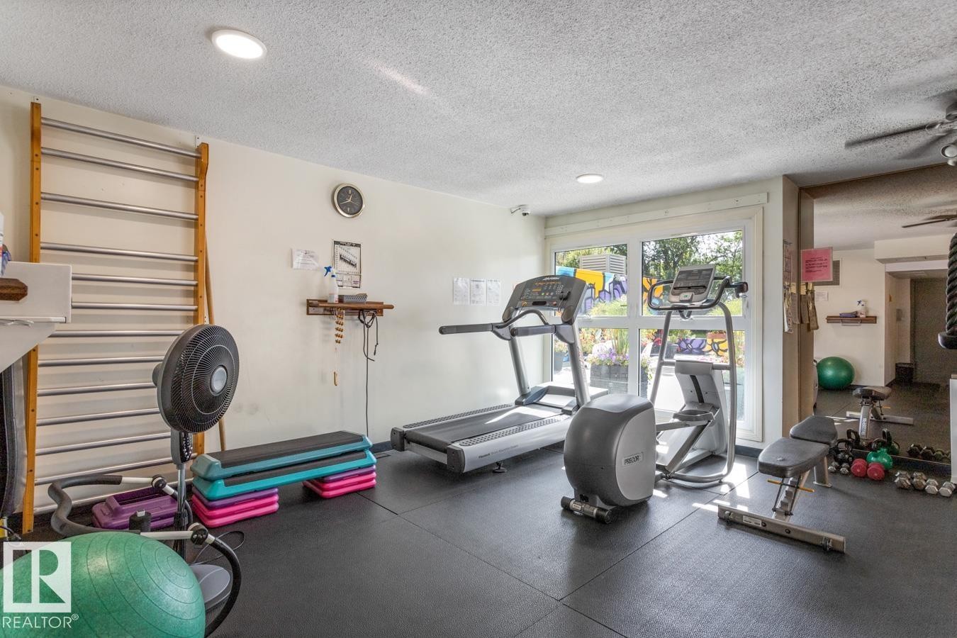 Dedicated fitness room featuring rubber flooring and abundant natural light from the large window. New Fitness Room is under construction. - 602 12303 Jasper Avenue, Edmonton, AB