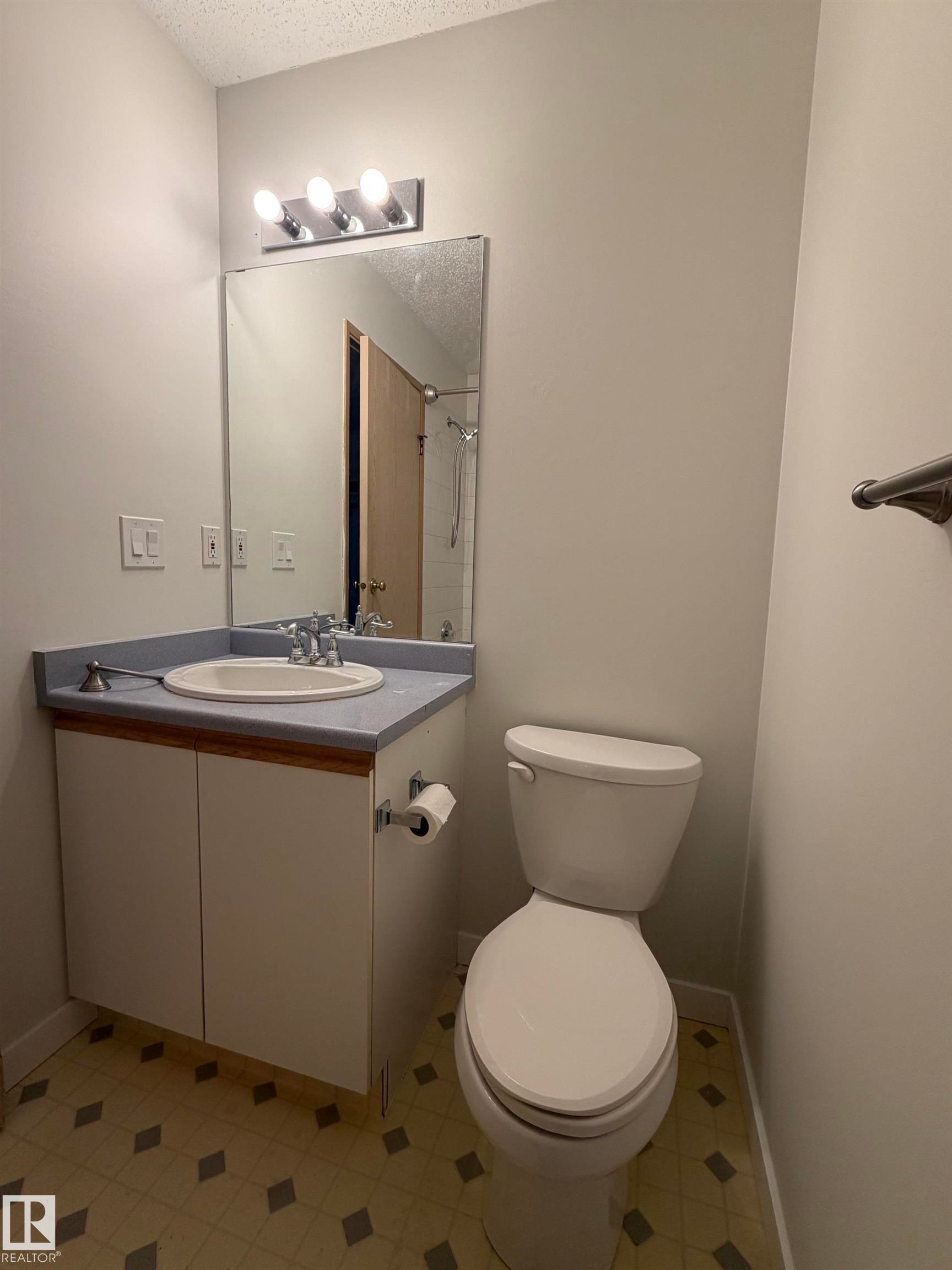 Bathroom featuring a white vanity with a blue countertop, an undermount sink, and a chrome faucet - 213 17467 98A Avenue, Edmonton, AB