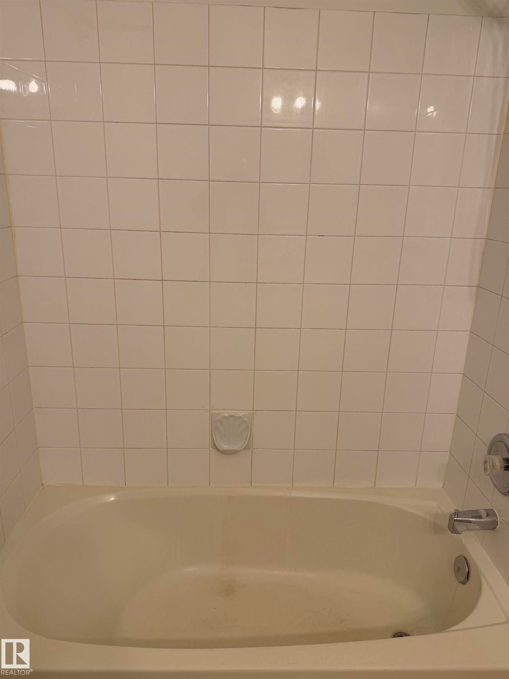 Alcove bathtub with white ceramic tile surround and chrome fixtures - 213 17467 98A Avenue, Edmonton, AB