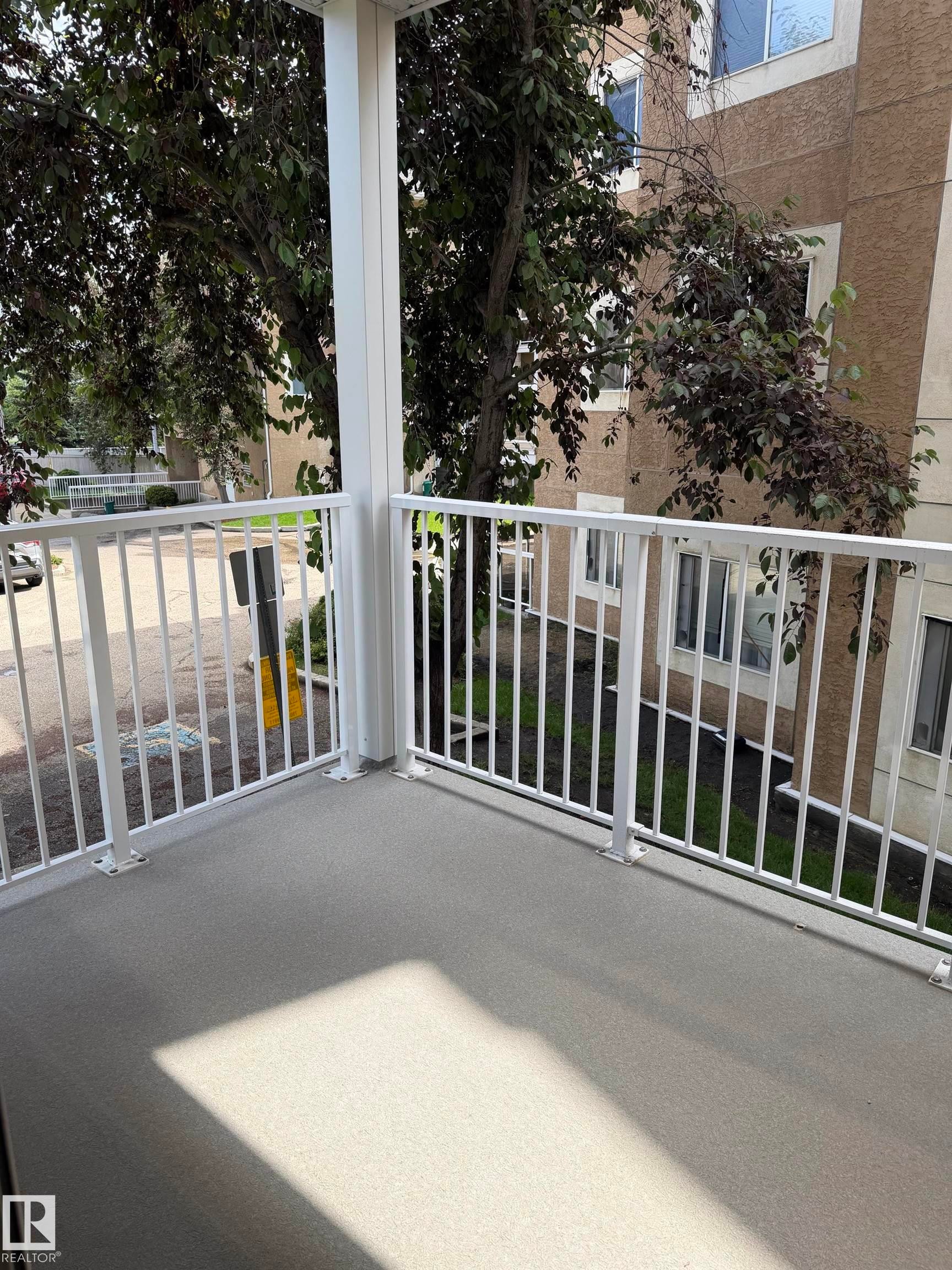 Private balcony featuring a textured gray surface and white metal railings - 213 17467 98A Avenue, Edmonton, AB