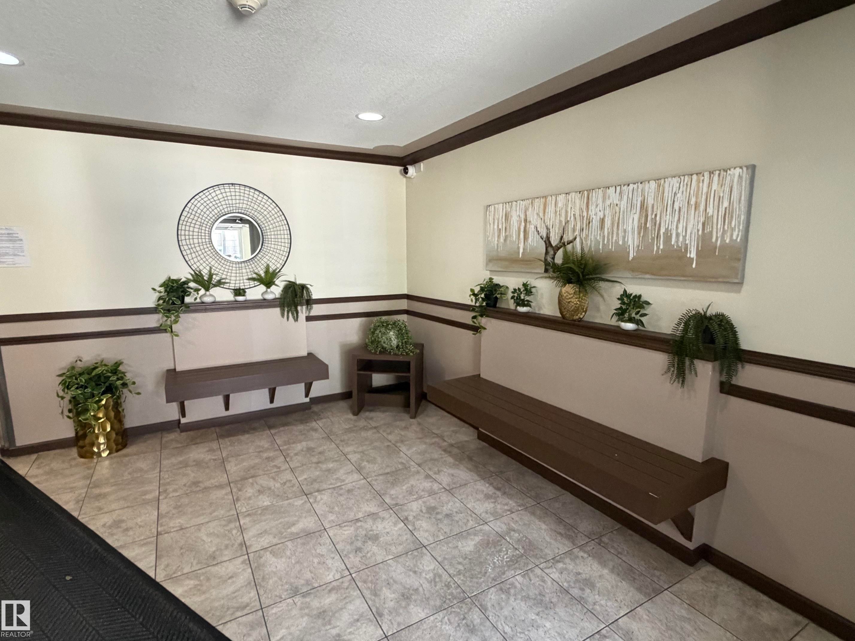 Tiled flooring in a neutral tone, featuring built-in wooden benches and a coordinating side table - 213 17467 98A Avenue, Edmonton, AB
