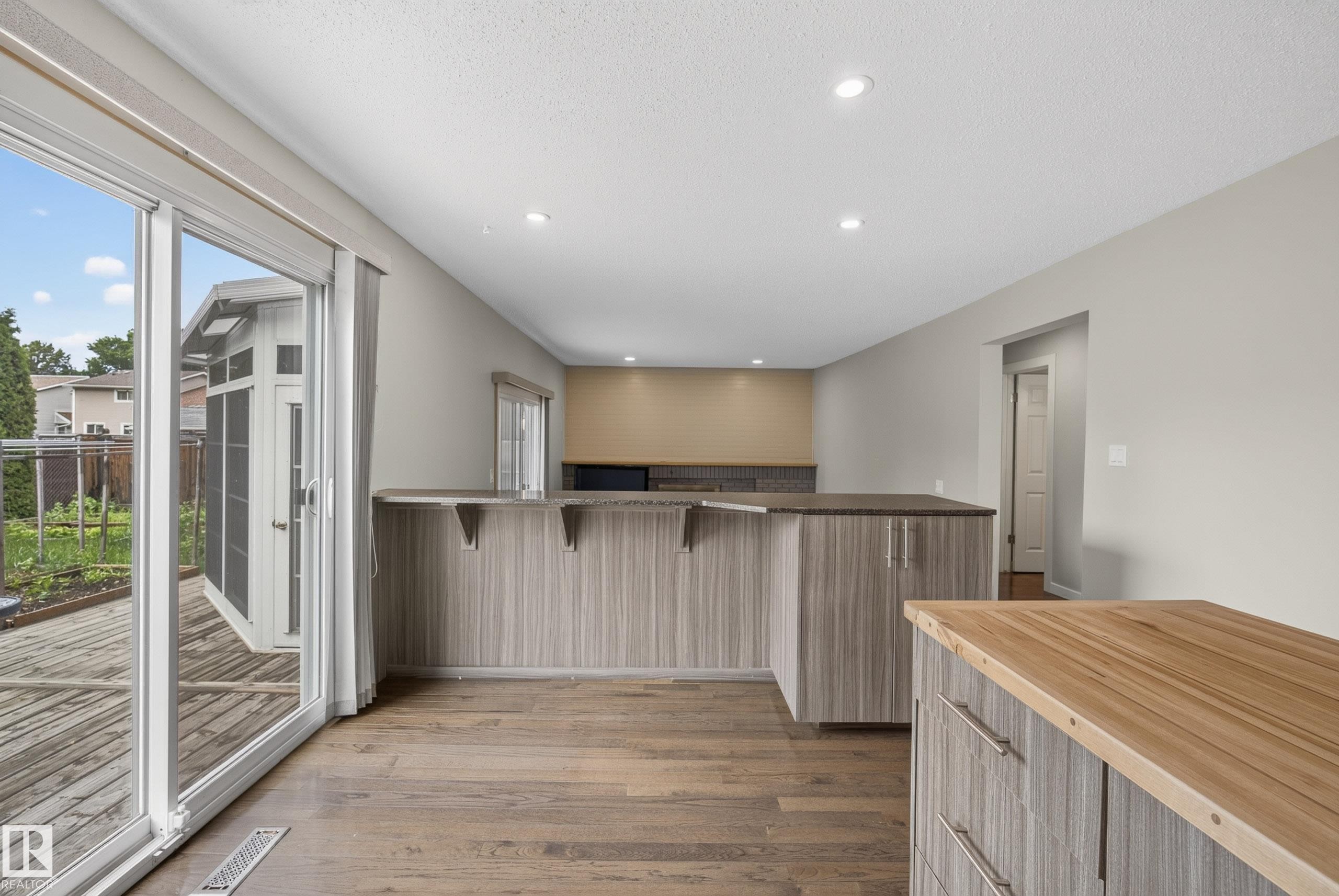 Spacious interior featuring wood-finish flooring, recessed lighting, and light-toned walls - 2712 104 Street, Edmonton, AB