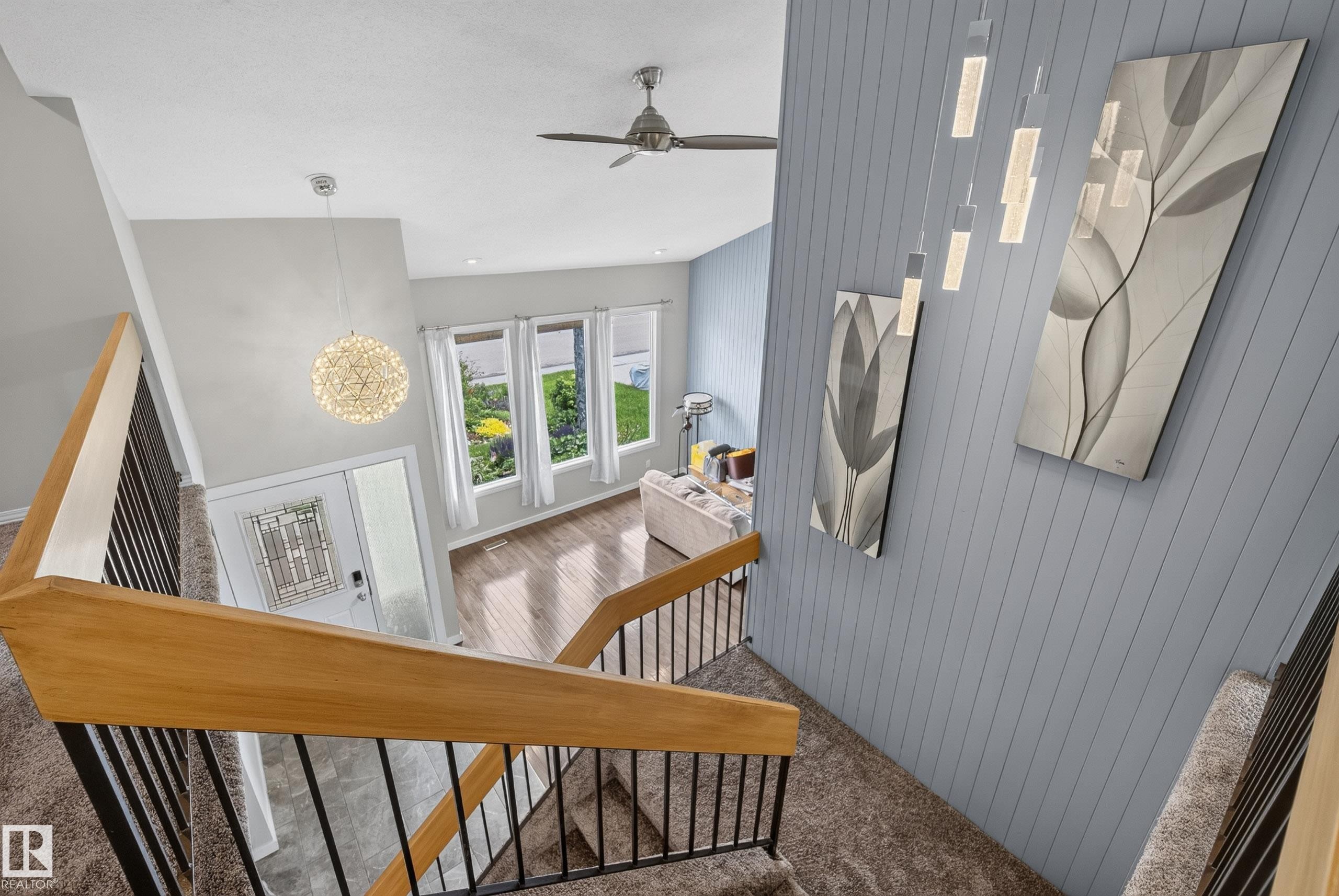 Multi-level interior featuring a contemporary staircase with wood handrails and black metal balusters - 2712 104 Street, Edmonton, AB
