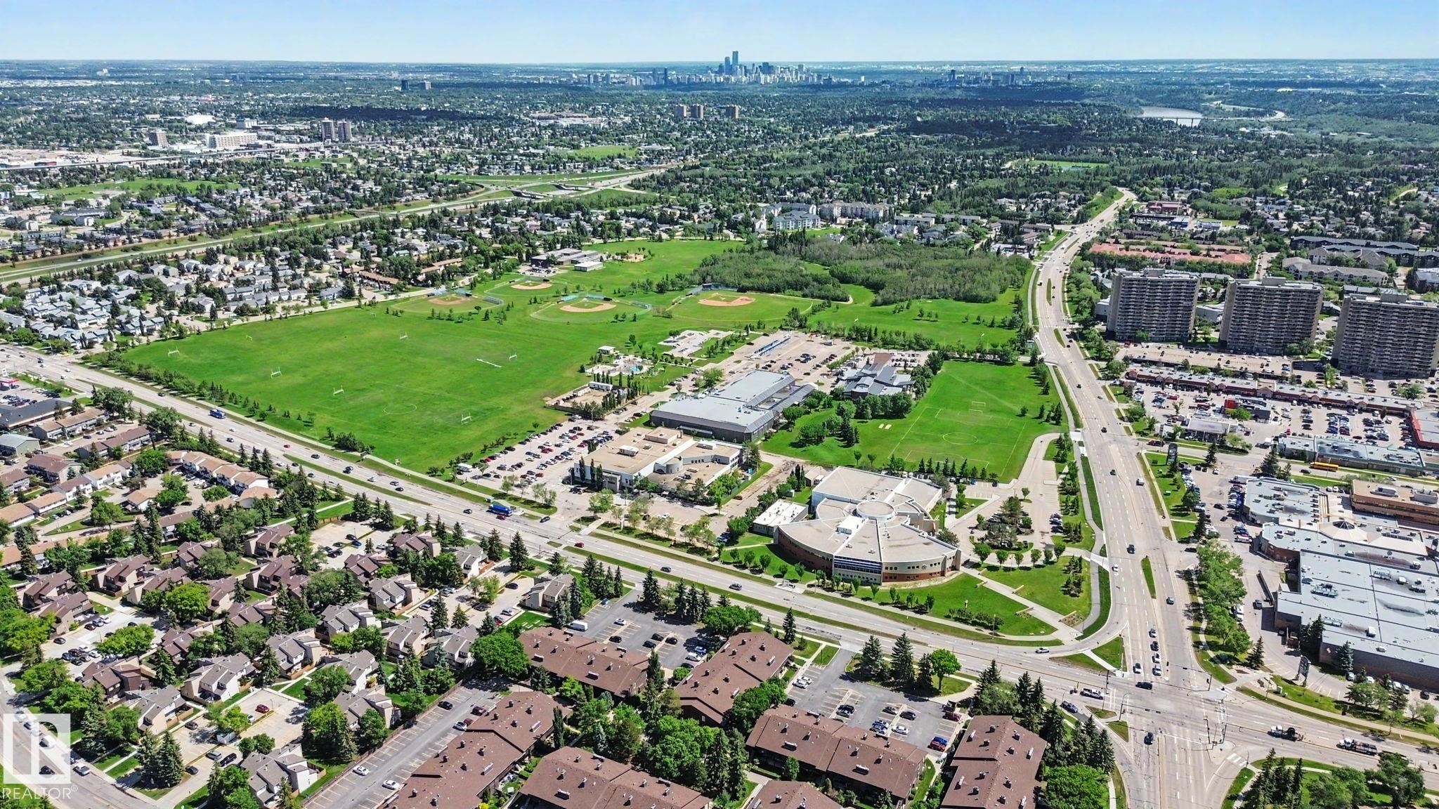 Expansive aerial overview of a vibrant urban landscape, featuring diverse residential areas, commercial buildings, and extensive green spaces - 18409 66 Avenue, Edmonton, AB