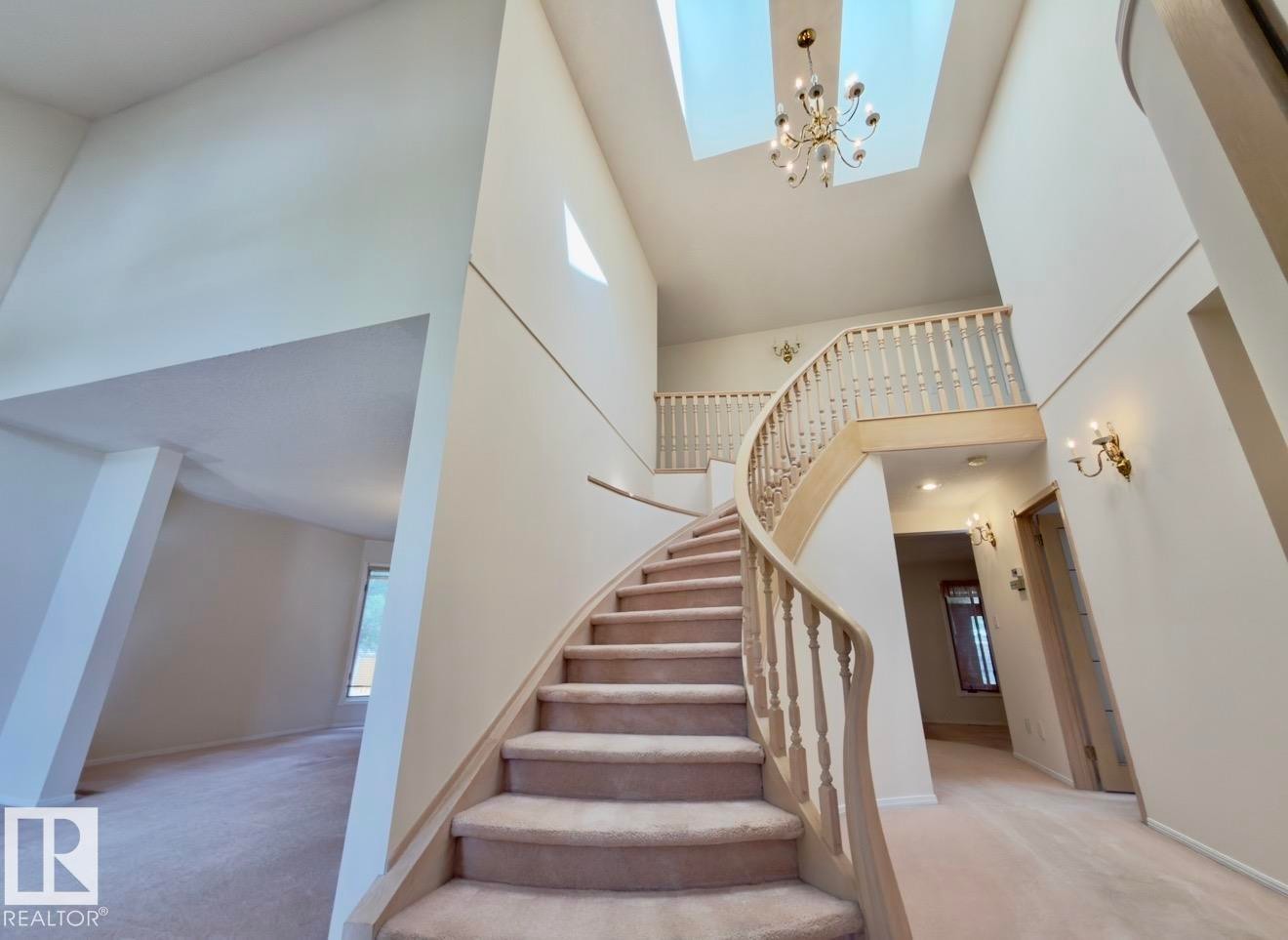 Grand foyer with curved staircase and light-toned carpet flooring - 134 Wolf Ridge Place, Edmonton, AB