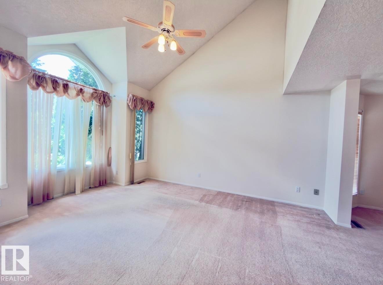 Spacious interior featuring a vaulted ceiling and a prominent arched window with multiple vertical panes - 134 Wolf Ridge Place, Edmonton, AB