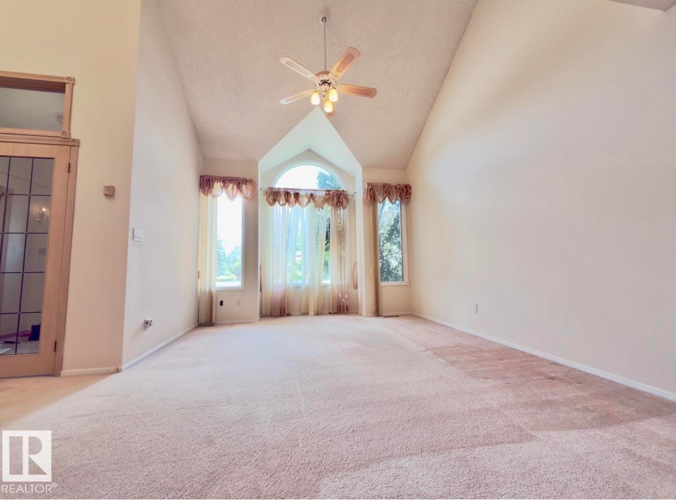 Vaulted ceilings accentuate the height of this carpeted room, featuring a bay window with an arched transom - 134 Wolf Ridge Place, Edmonton, AB