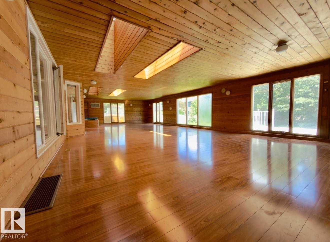 Spacious room featuring wood-finish flooring, wood plank walls, and a wood plank ceiling - 134 Wolf Ridge Place, Edmonton, AB