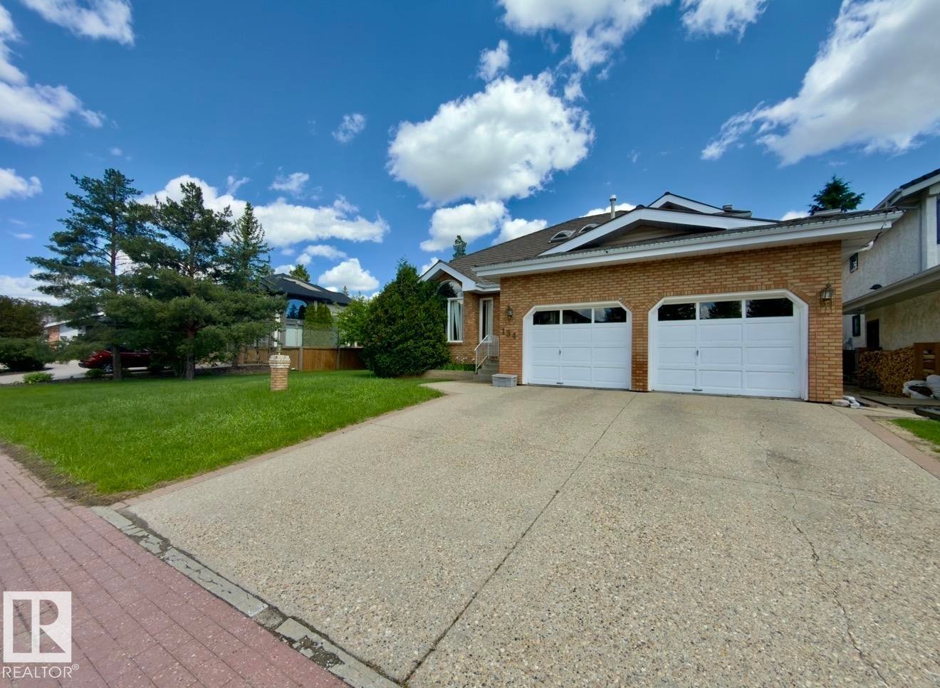 Brick exterior featuring a two-car garage with arched window panels - 134 Wolf Ridge Place, Edmonton, AB