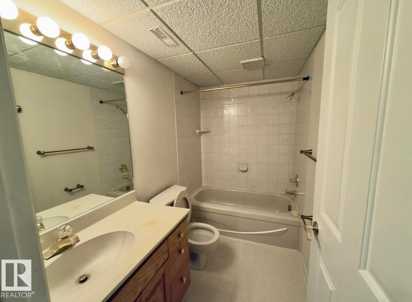 Full bathroom featuring a single vanity with wood cabinetry, a built-in sink, and a light-colored countertop - 134 Wolf Ridge Place, Edmonton, AB