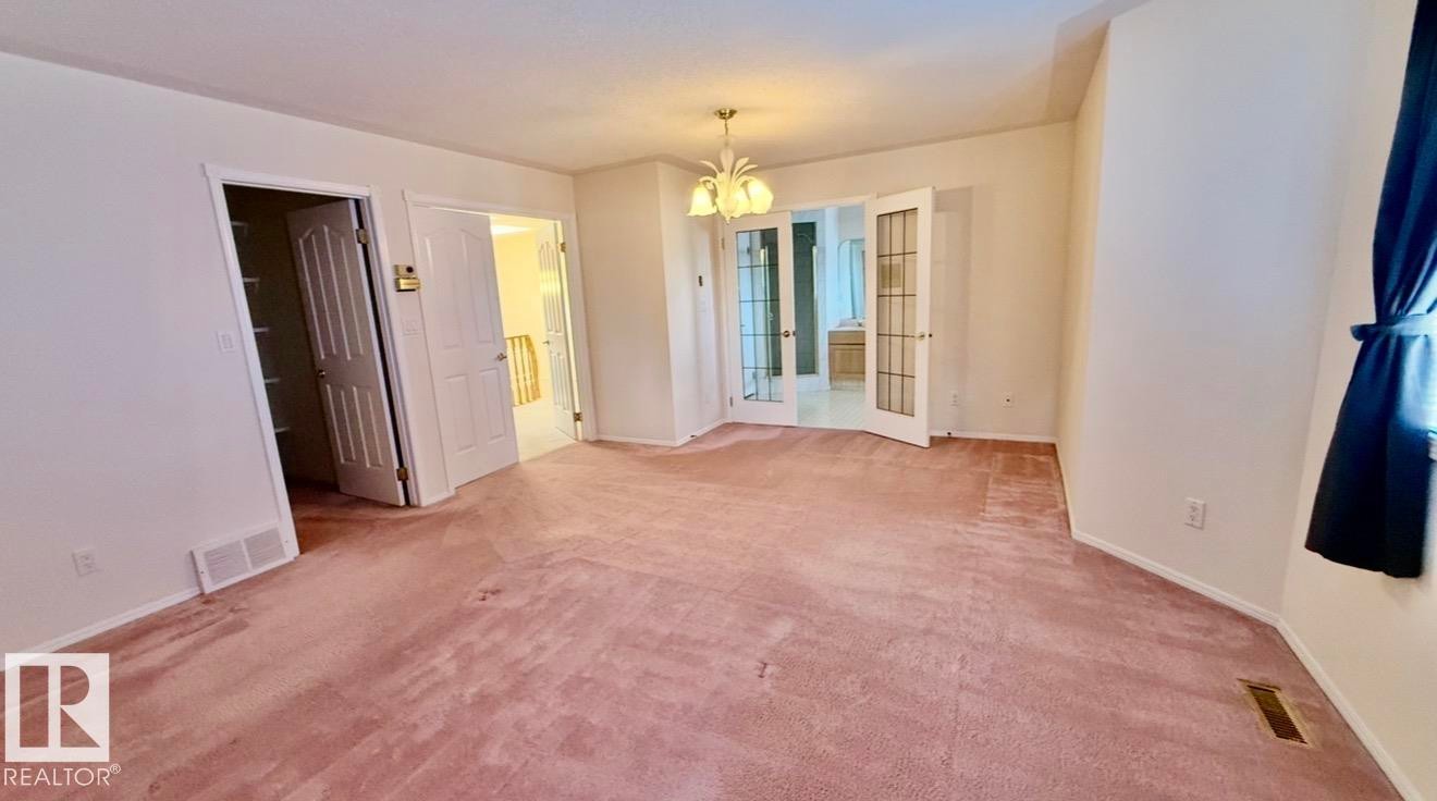 Expansive carpeted room featuring a white ceiling fixture, white walls, and white trim - 134 Wolf Ridge Place, Edmonton, AB