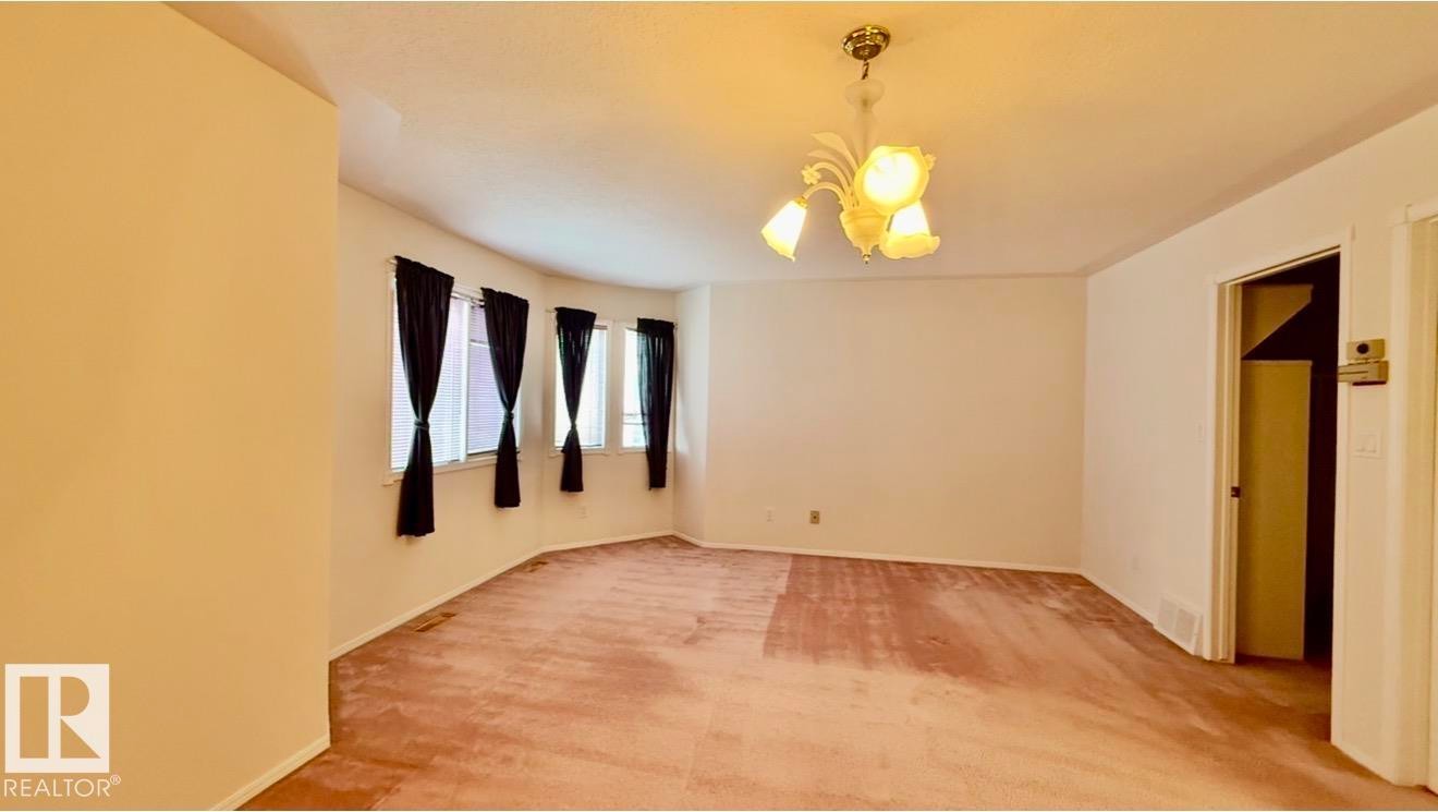 Curved wall featuring multiple windows, a ceiling-mounted light fixture, and light-toned walls - 134 Wolf Ridge Place, Edmonton, AB