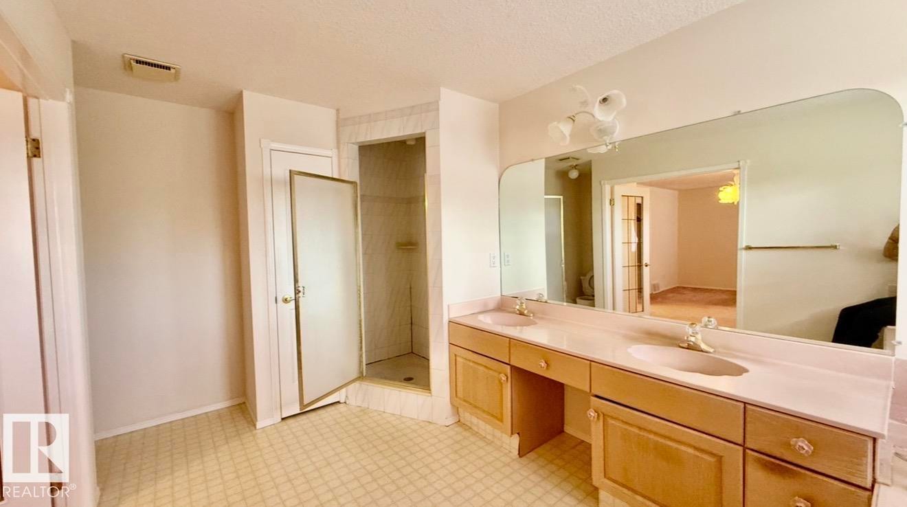 Dual vanity with integrated sinks, light wood-finish cabinetry, and a full-width wall mirror - 134 Wolf Ridge Place, Edmonton, AB