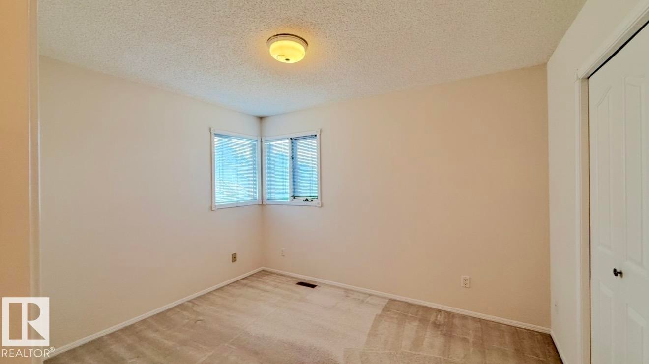 Corner window with blinds, ceiling-mounted light fixture, wall-to-wall carpeting, and a bi-fold closet door - 134 Wolf Ridge Place, Edmonton, AB