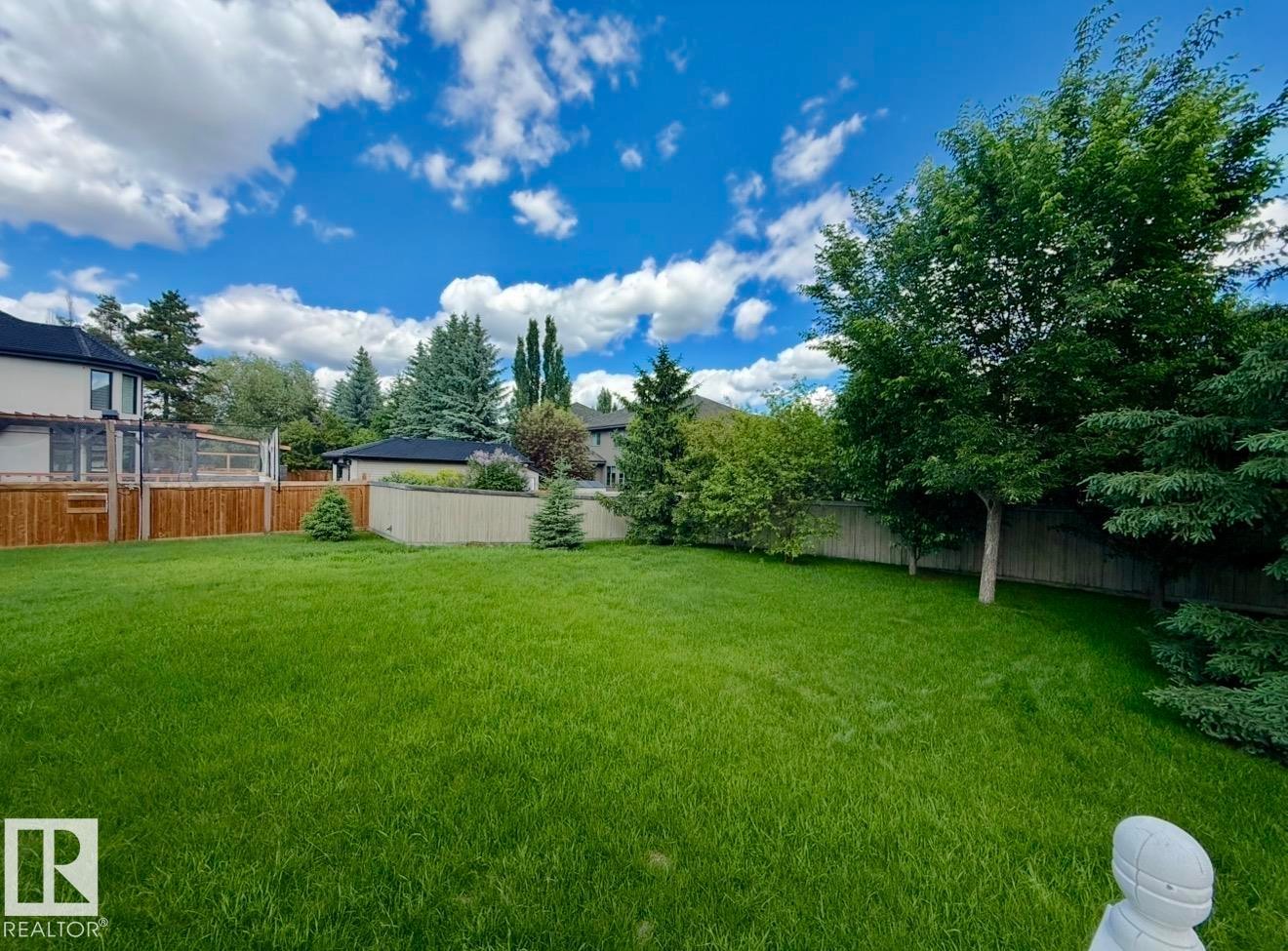 Expansive green lawn surrounded by mature trees and fencing - 134 Wolf Ridge Place, Edmonton, AB