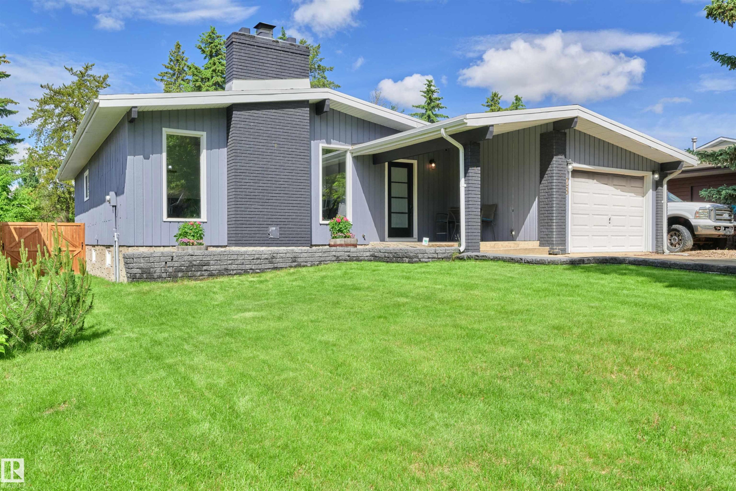 Contemporary architectural design featuring a prominent chimney, a single-car garage, and a covered entryway - 28 Goodridge Drive, St. Albert, AB