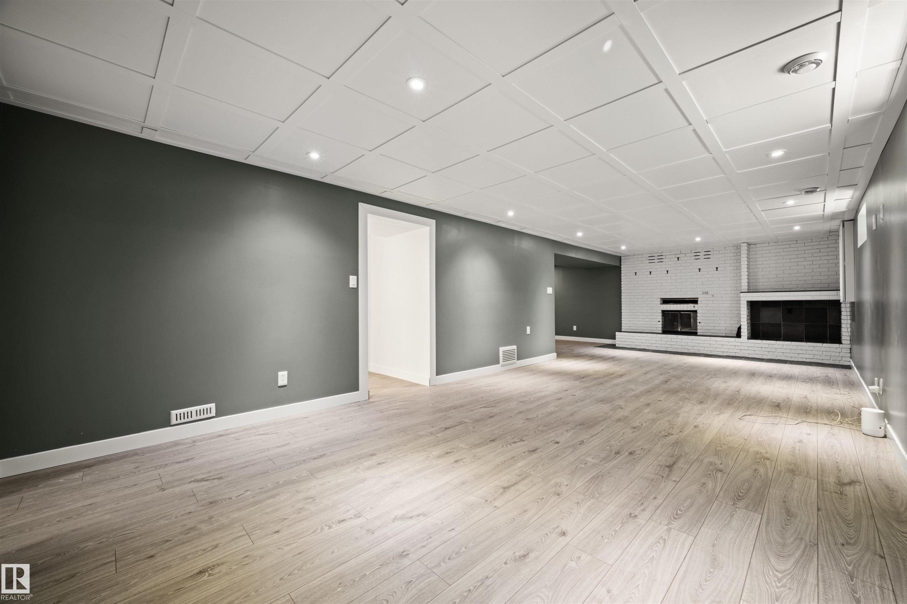 Spacious room featuring wood-finish flooring, recessed lighting, and a white coffered ceiling - 28 Goodridge Drive, St. Albert, AB