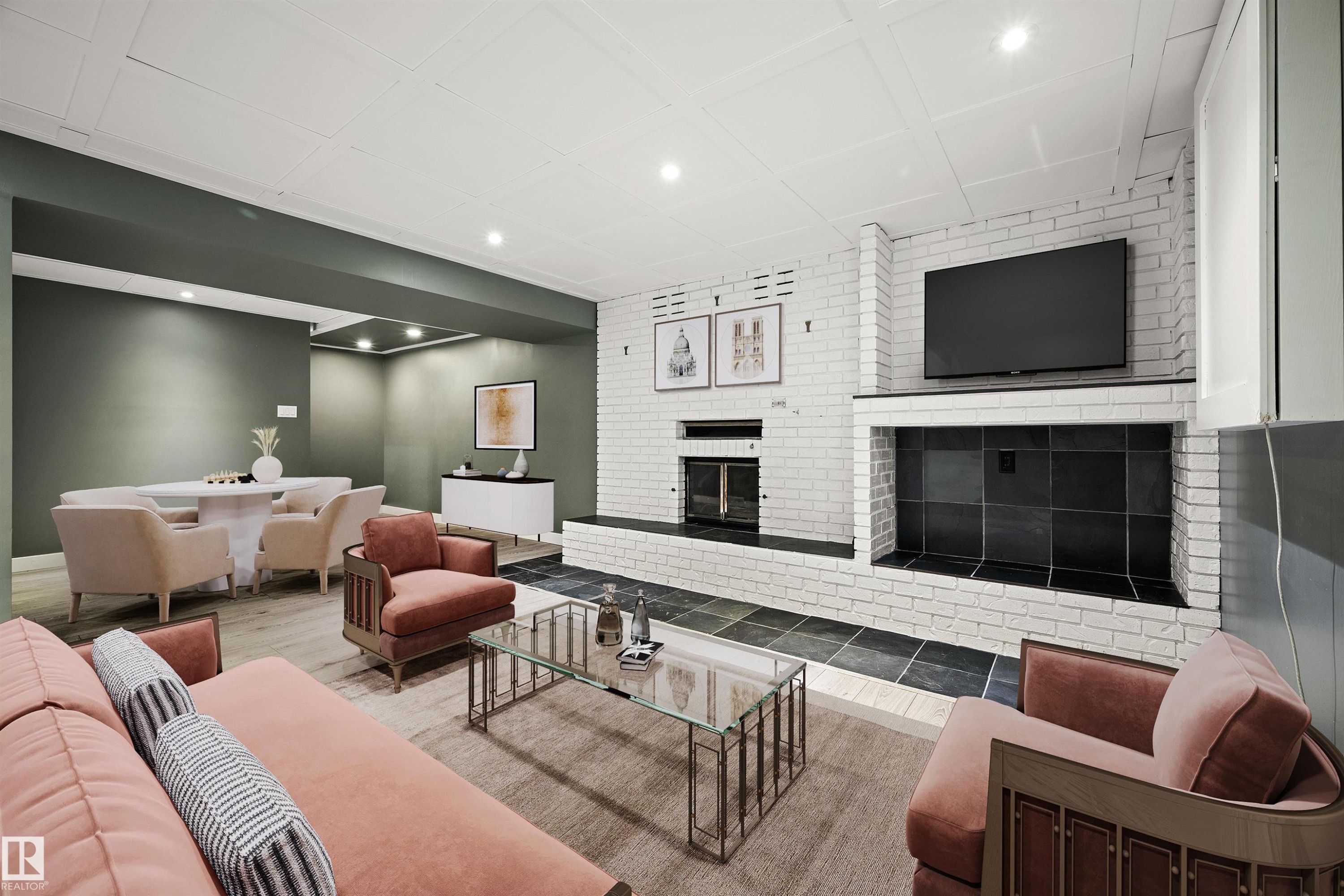 Spacious entertainment area featuring a white painted brick fireplace with hearth, recessed lighting, and wood-finish flooring - 28 Goodridge Drive, St. Albert, AB