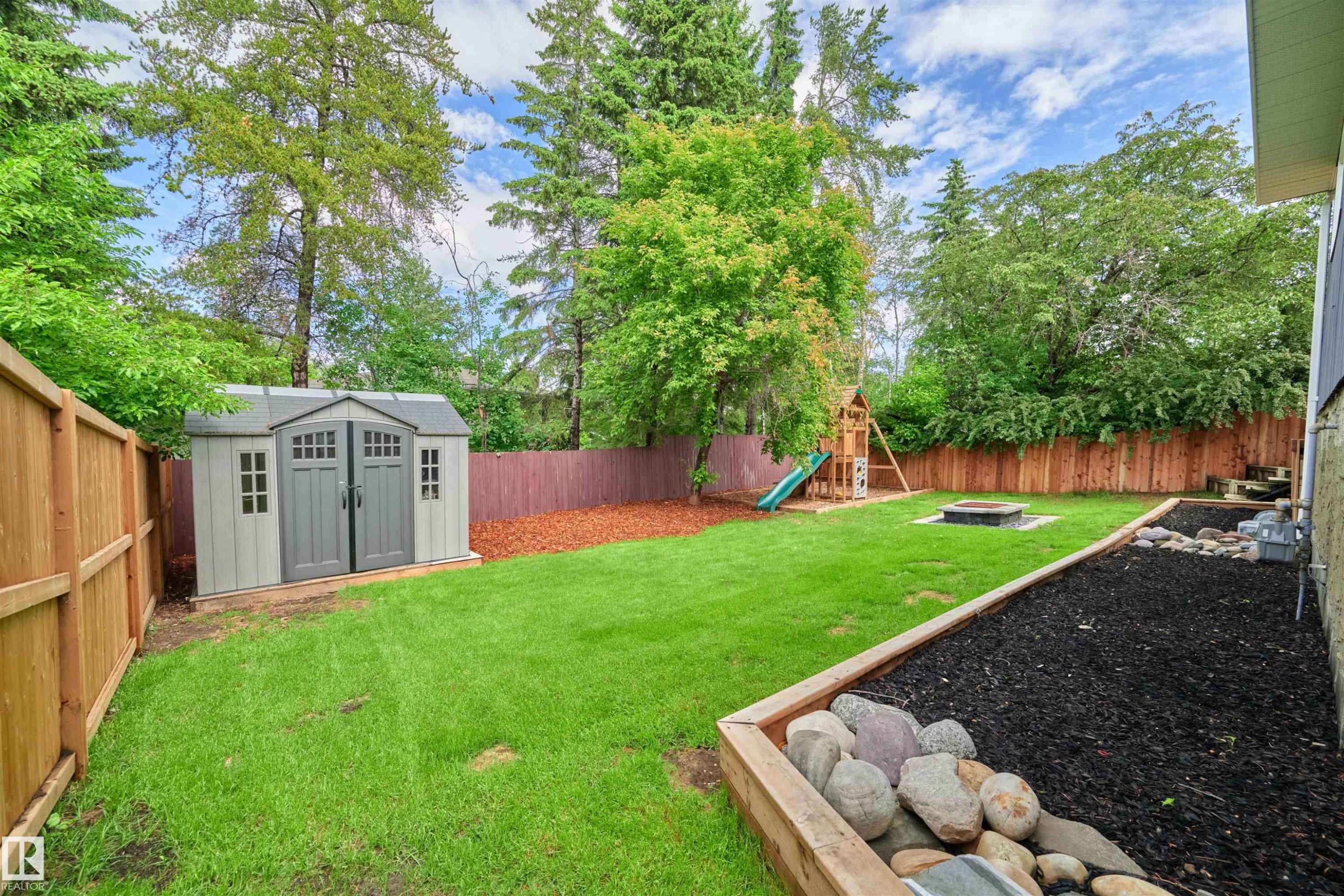 Expansive backyard featuring a manicured lawn, a durable storage shed, and a wooden privacy fence - 28 Goodridge Drive, St. Albert, AB